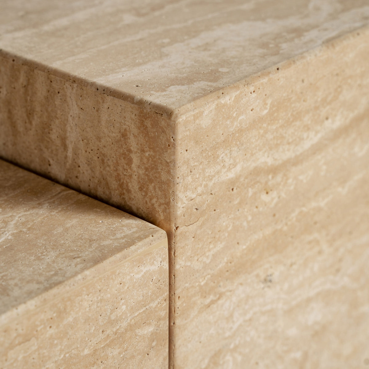Detalle de la esquina del mueble de TV en travertino, mostrando textura natural y precisión en los acabados.