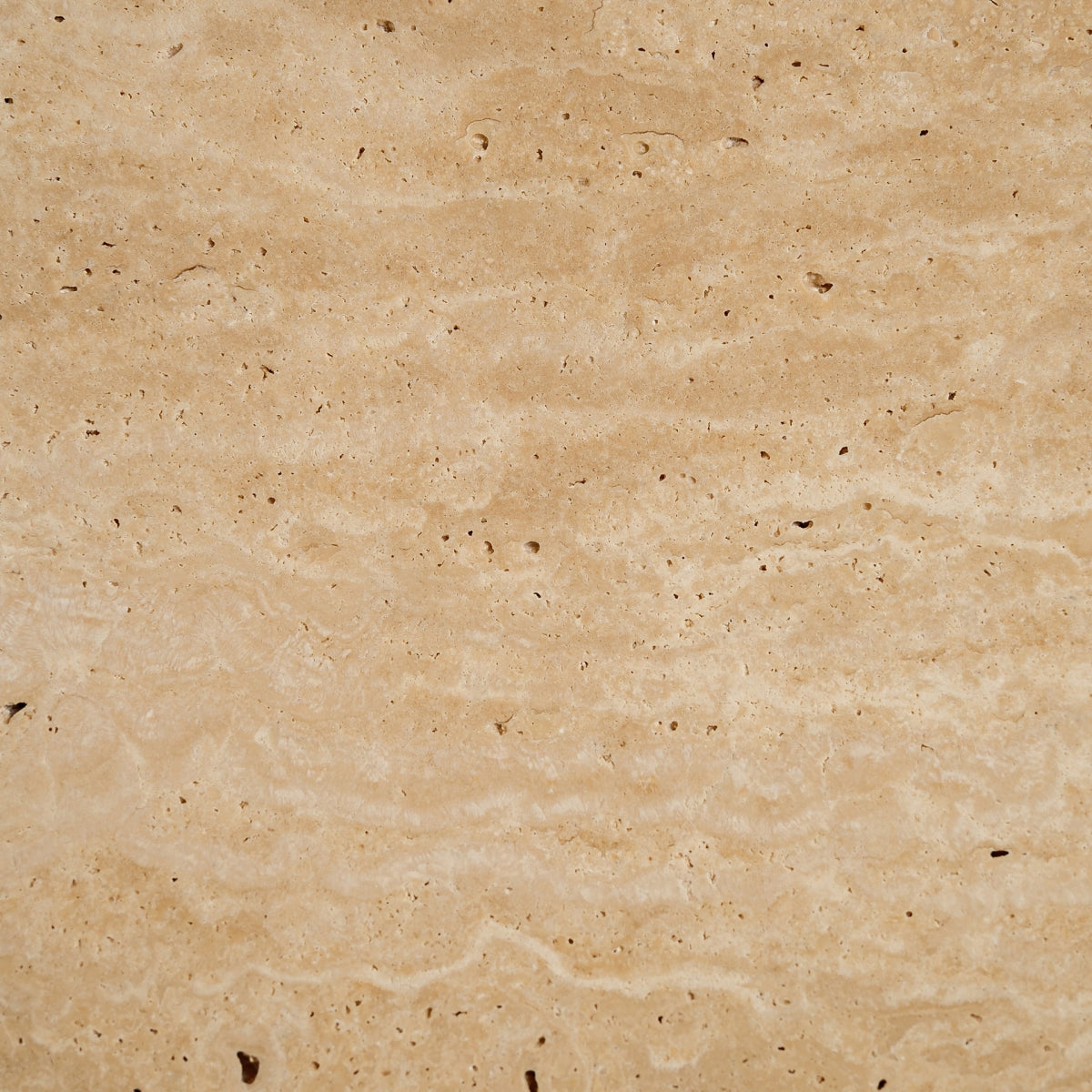 Vista cercana de la superficie del travertino con vetas naturales y porosidad característica en tono cálido.
