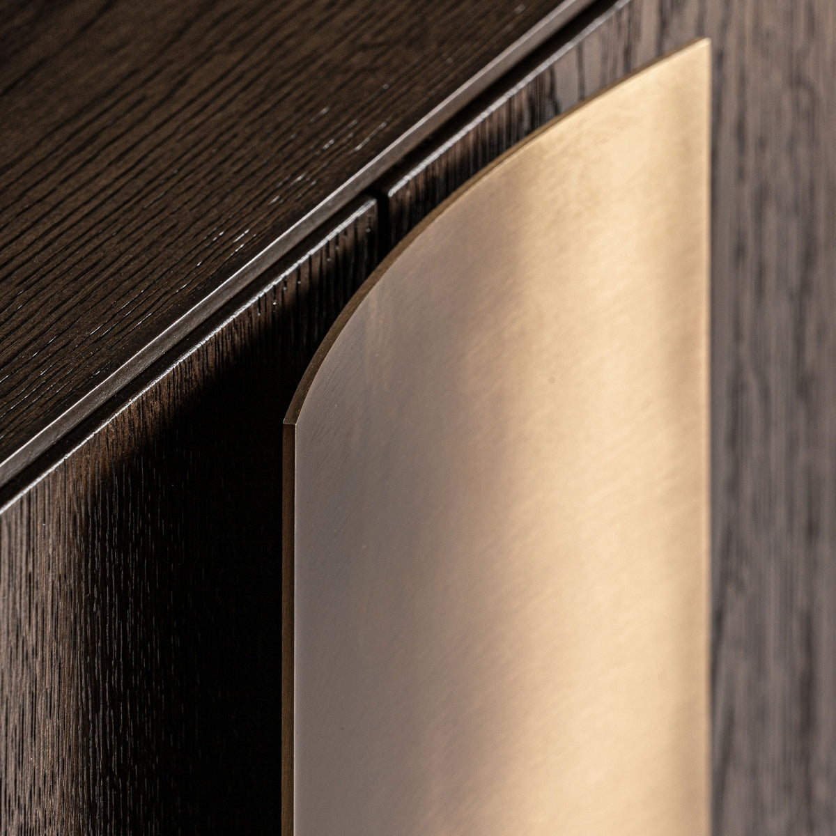 Detalle del tirador geométrico dorado sobre madera oscura, contraste elegante y moderno