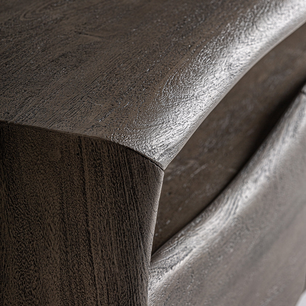 Detalle curvo de la madera en el lateral del mueble, superficie natural con textura orgánica
