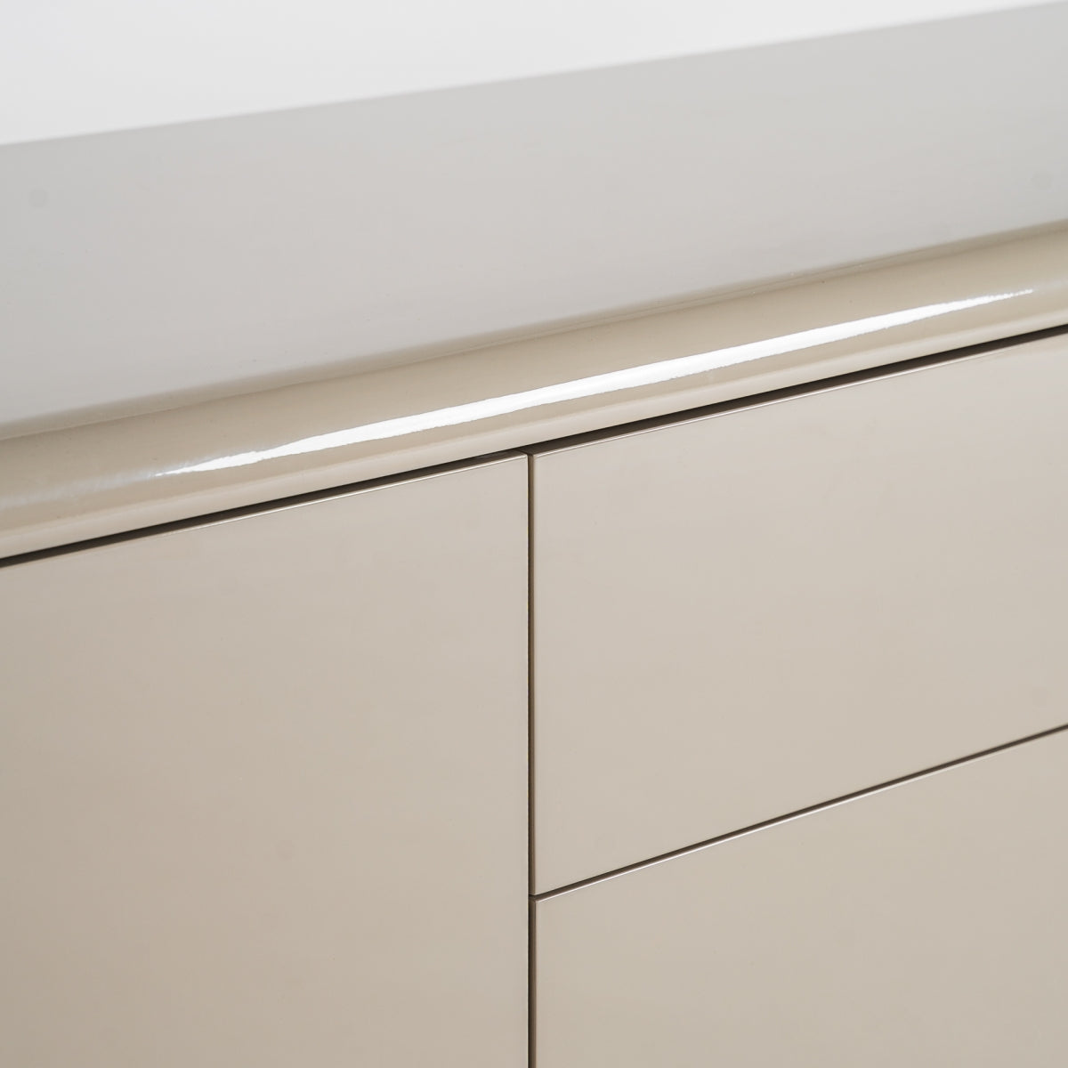 Detalle de la superficie lacada en beige con acabado brillante del mueble TV. Alta calidad y tacto suave.