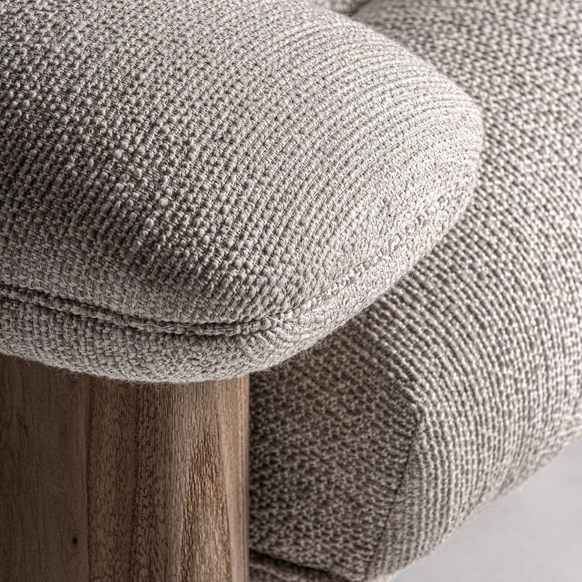 Detalle del apoyabrazos mullido del sofá Jacquard, tejido texturizado beige y base de madera natural