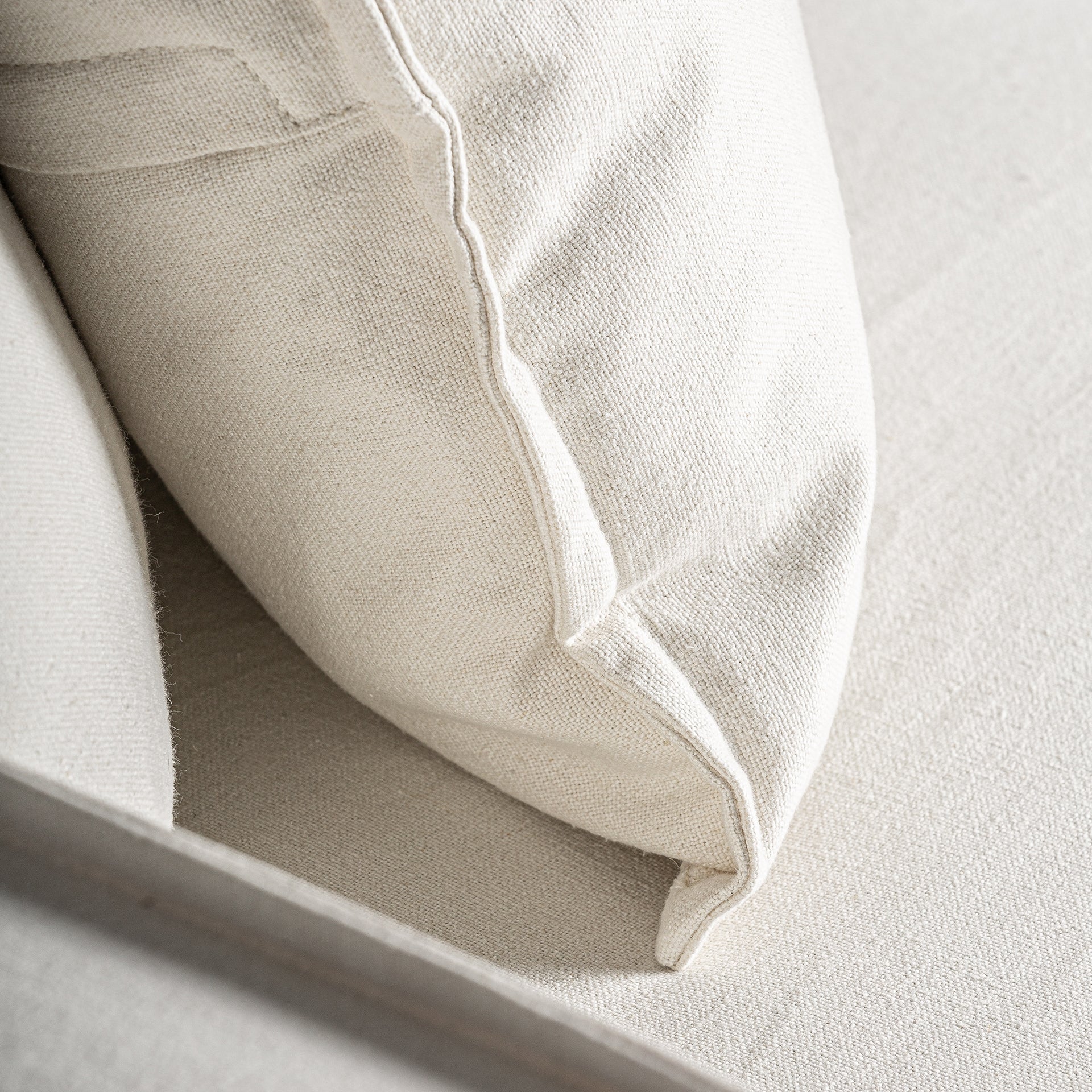 Detalle del cojín trasero del sofá Virolle, tapizado en lino blanco boutique interiorismo vical