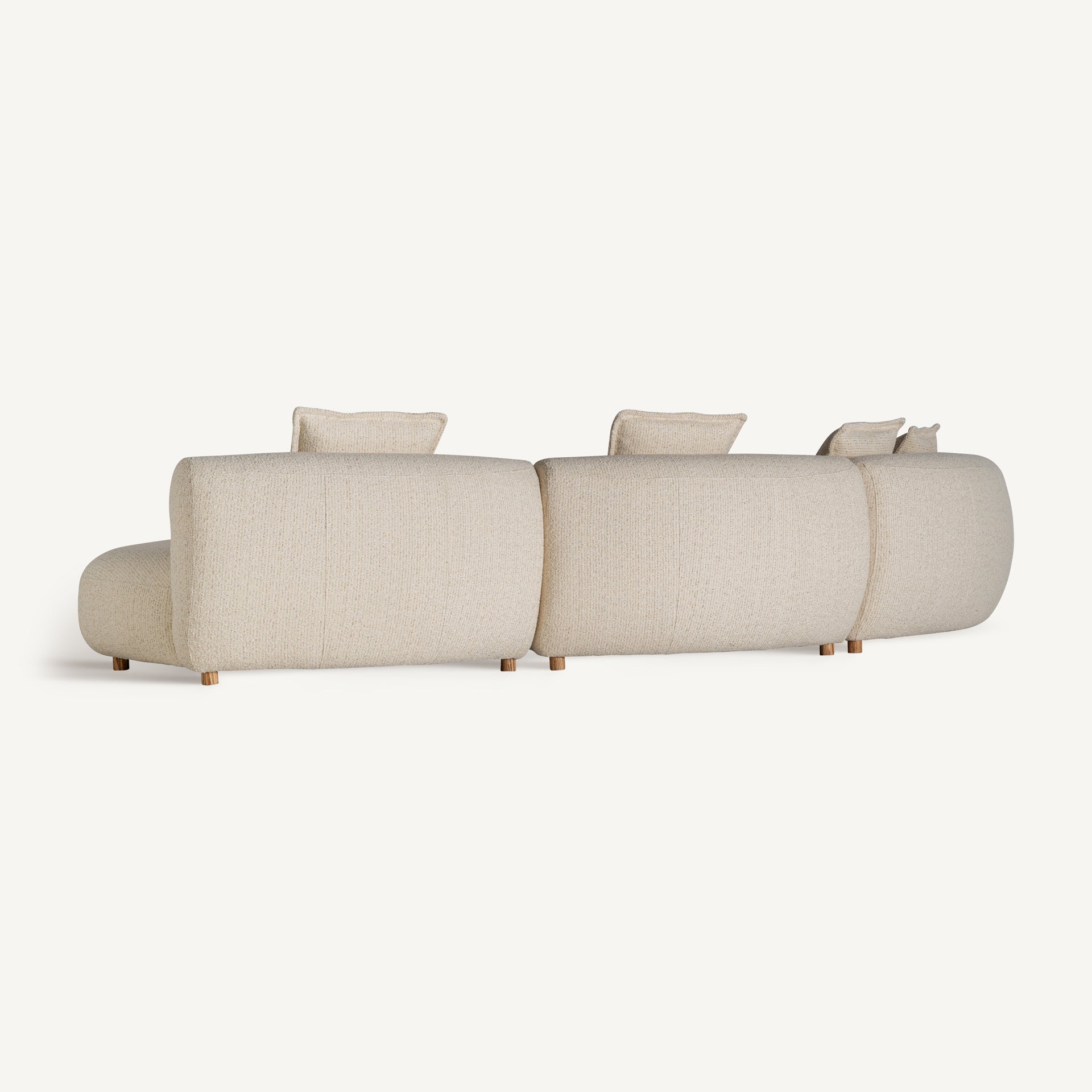 Vista trasera del sofá modular Zakupi, con respaldo curvo tapizado y acabado uniforme en color beige claro, diseño moderno