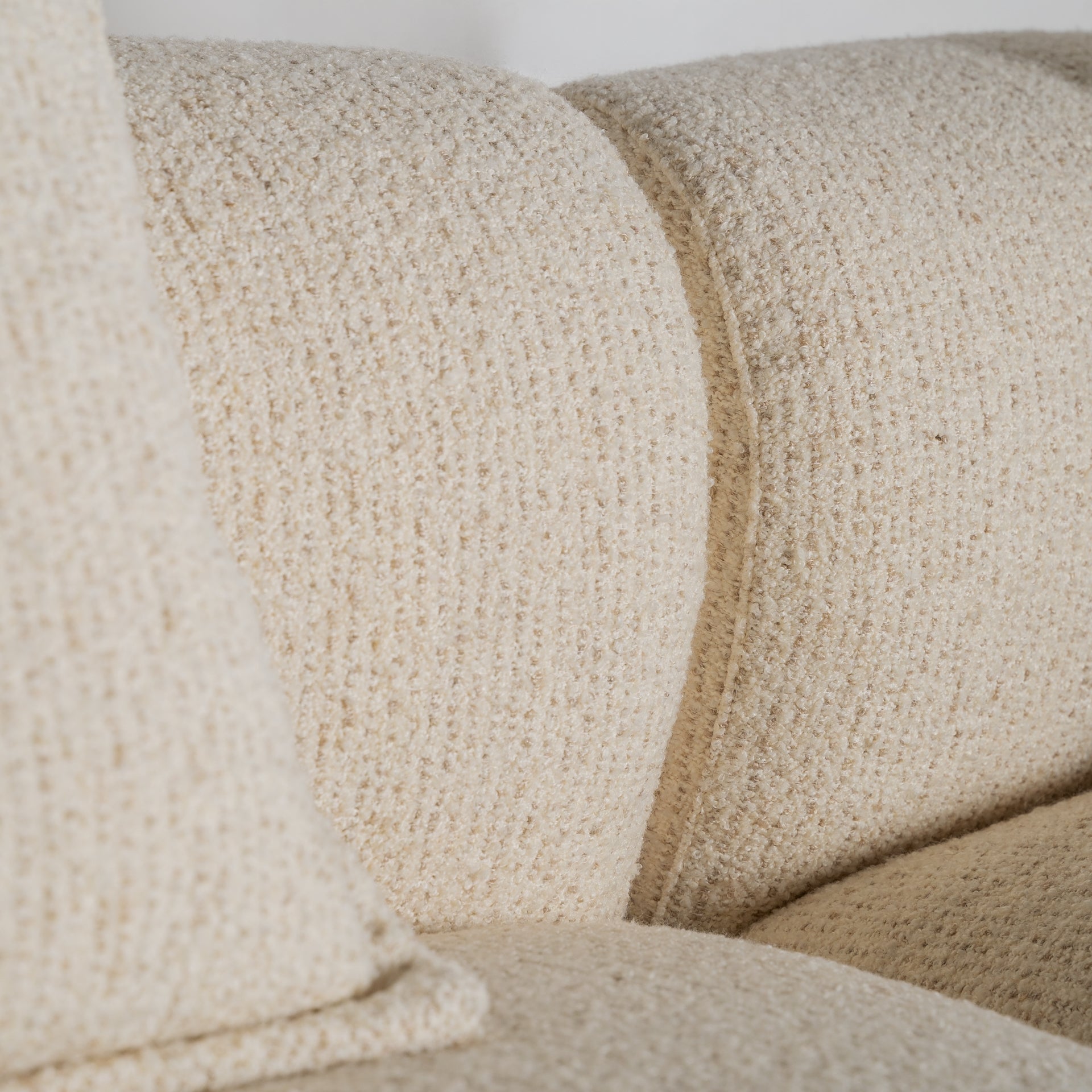 Detalle del respaldo del sofá Zakupi con forma ergonómica y tapizado en tejido bouclé color beige claro, estilo contemporáneo