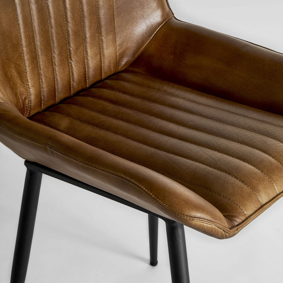 Detalle del asiento en cuero camel con textura natural y acolchado confortable