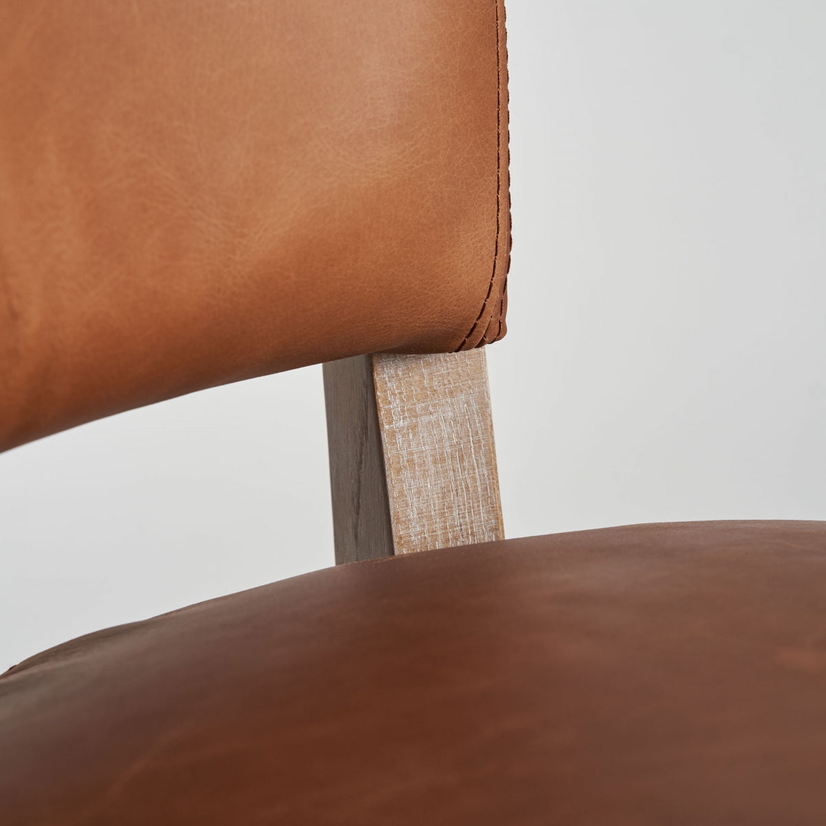 Detalle del asiento acolchado en piel marrón, confort y diseño tradicional.