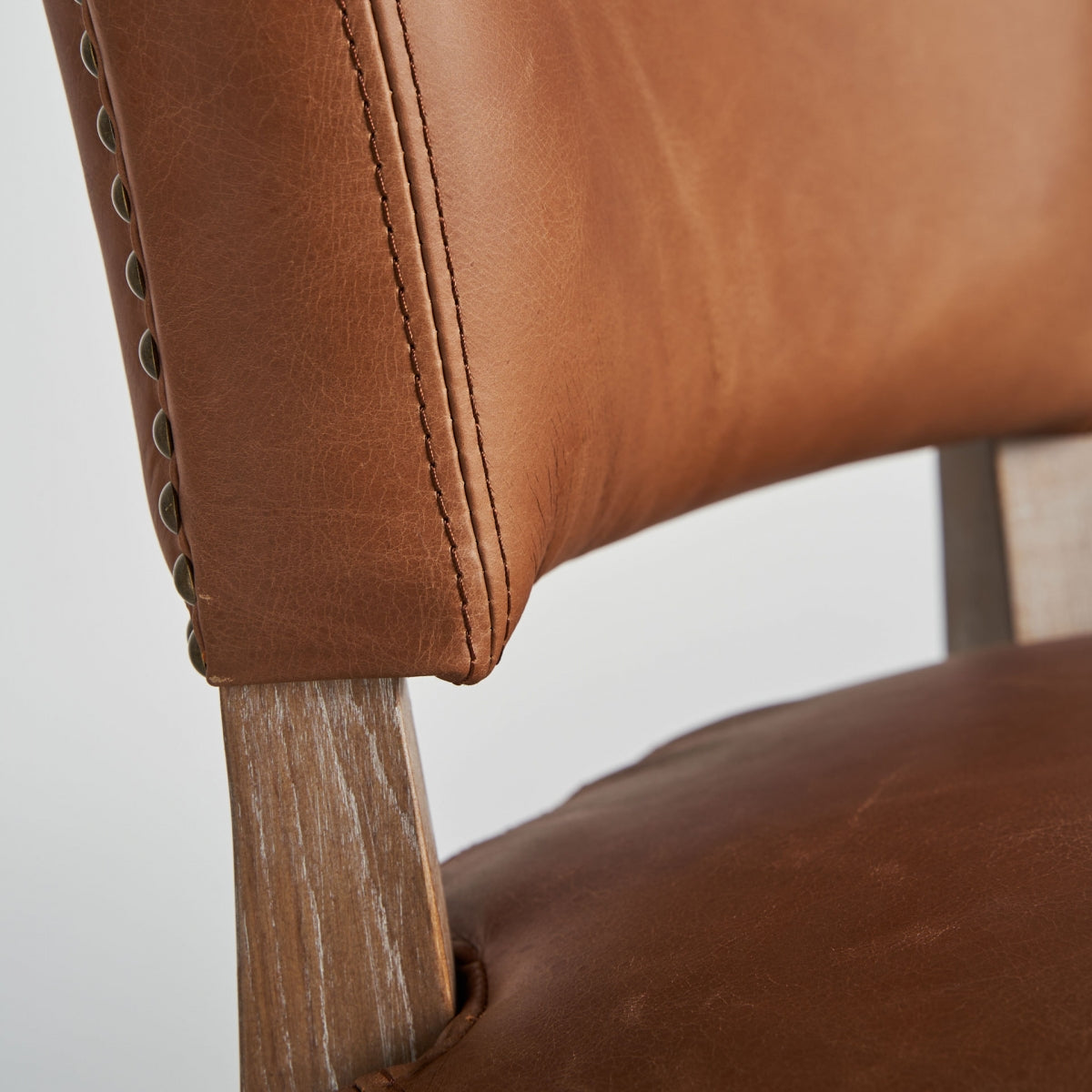 Silla tapizada marrón en espacio interior con luz natural, estilo clásico elegante.