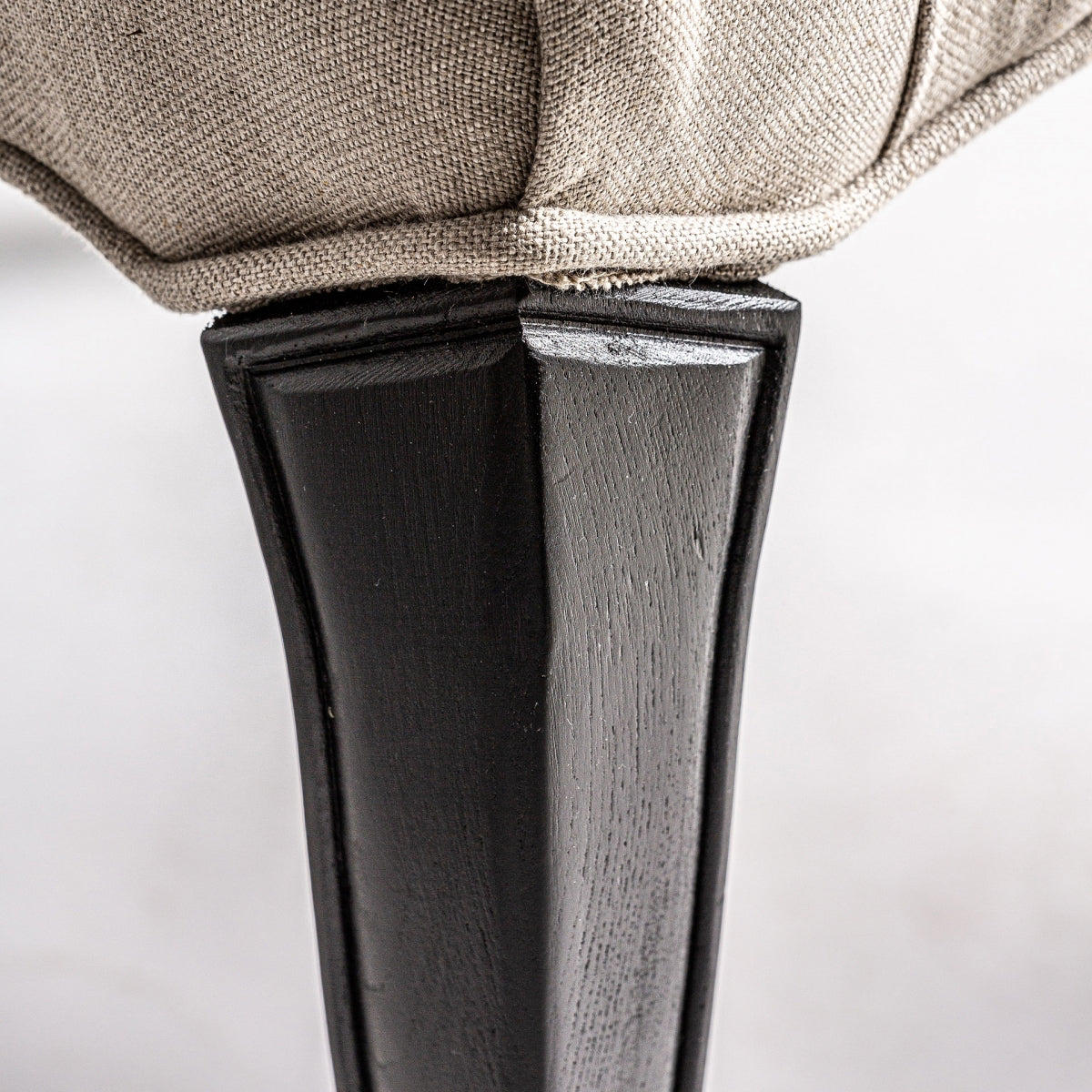 Detalle de pata delantera curva en madera negra tallada, diseño elegante