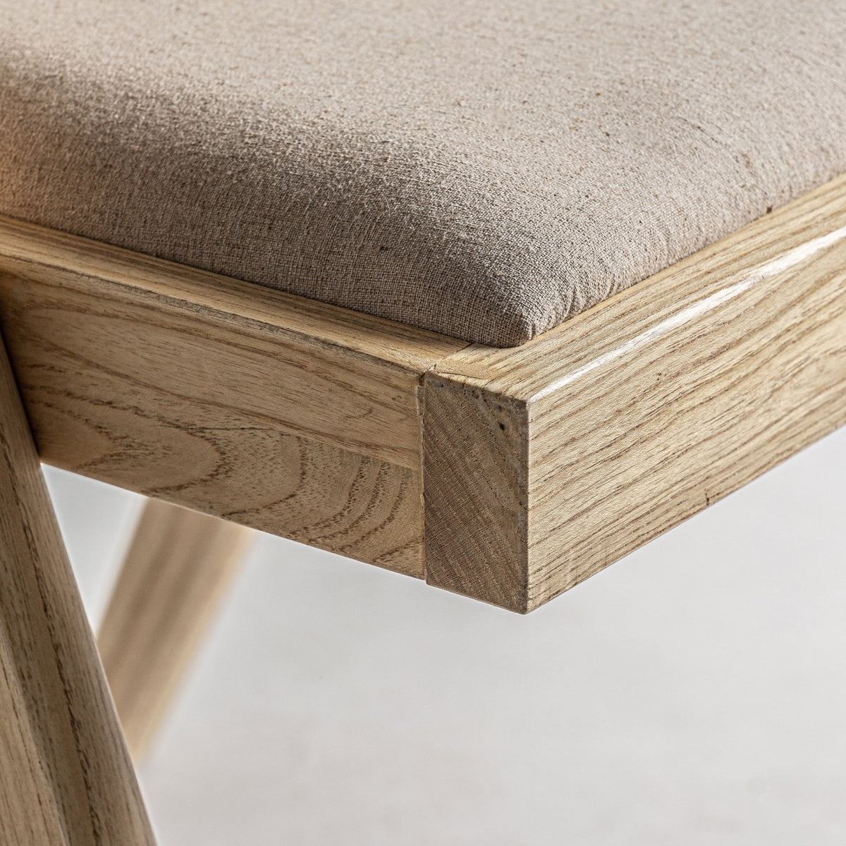 Asiento tapizado en tono natural sobre base de madera clara, confort y estilo acogedor