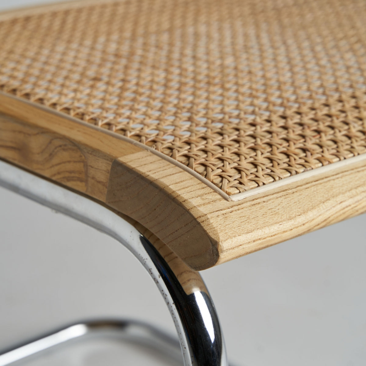 Detalle del respaldo de ratán tejido sobre estructura de madera natural.