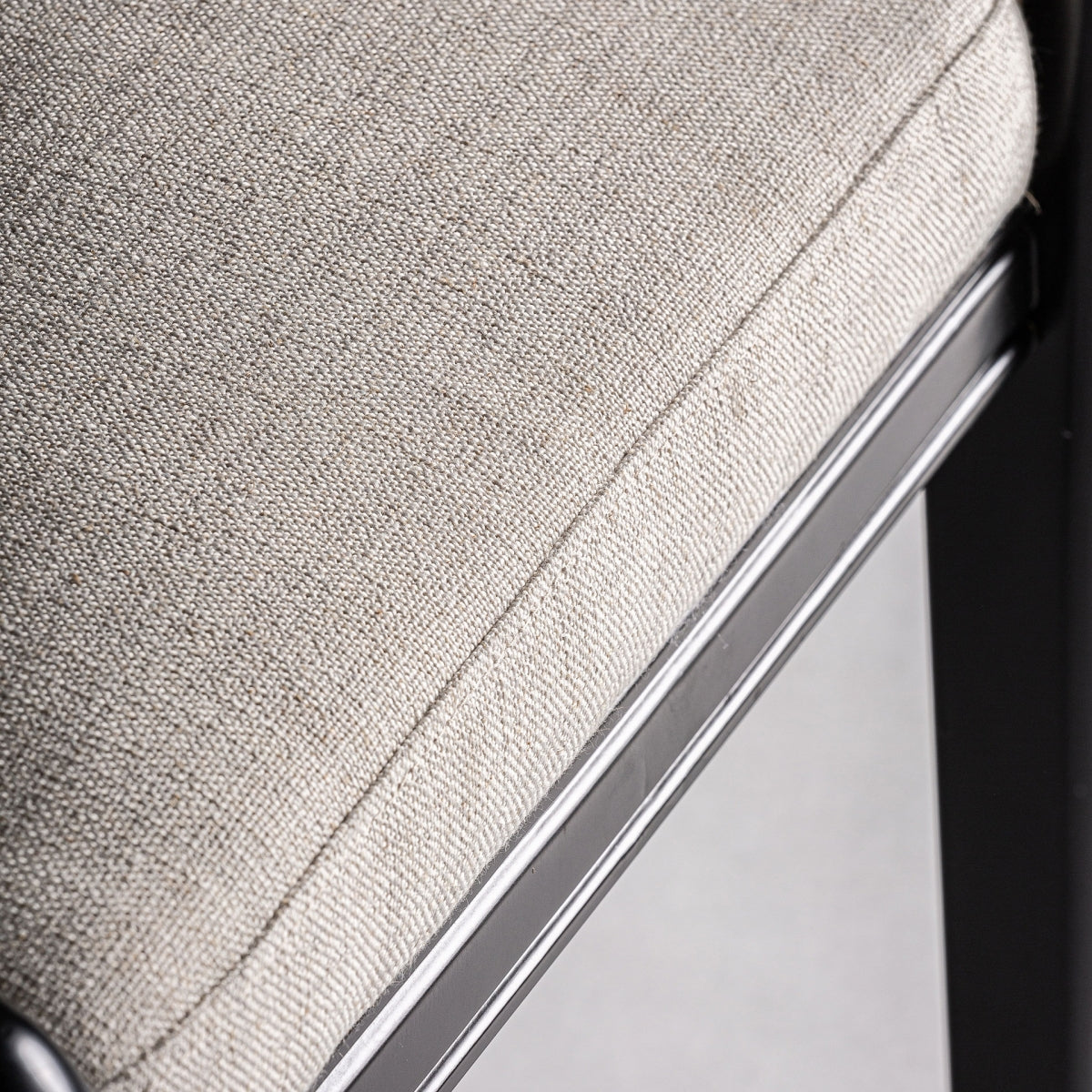 Asiento acolchado en tela beige de textura natural, detalle del borde inferior