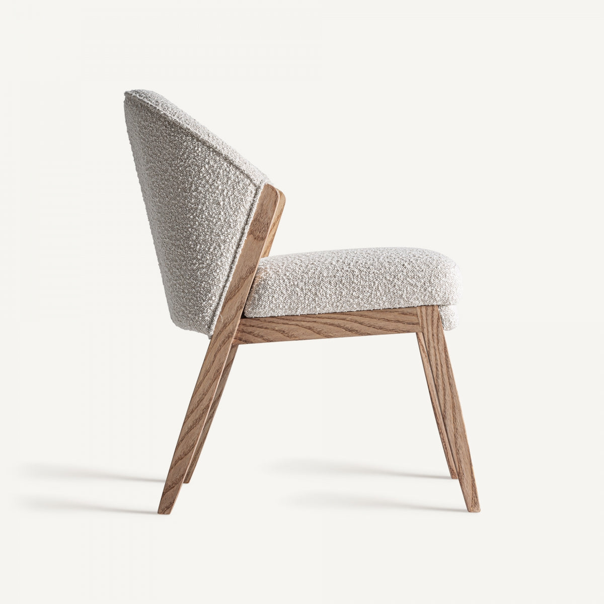 Perfil lateral de la silla Prati bouclé, brazos curvos y líneas suaves en madera natural.