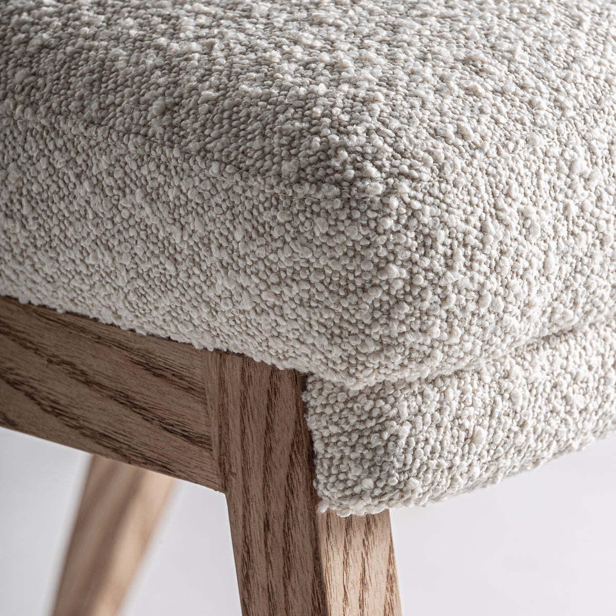 Primer plano del asiento de la silla Prati, tapizado en bouclé blanco con acabado mullido.