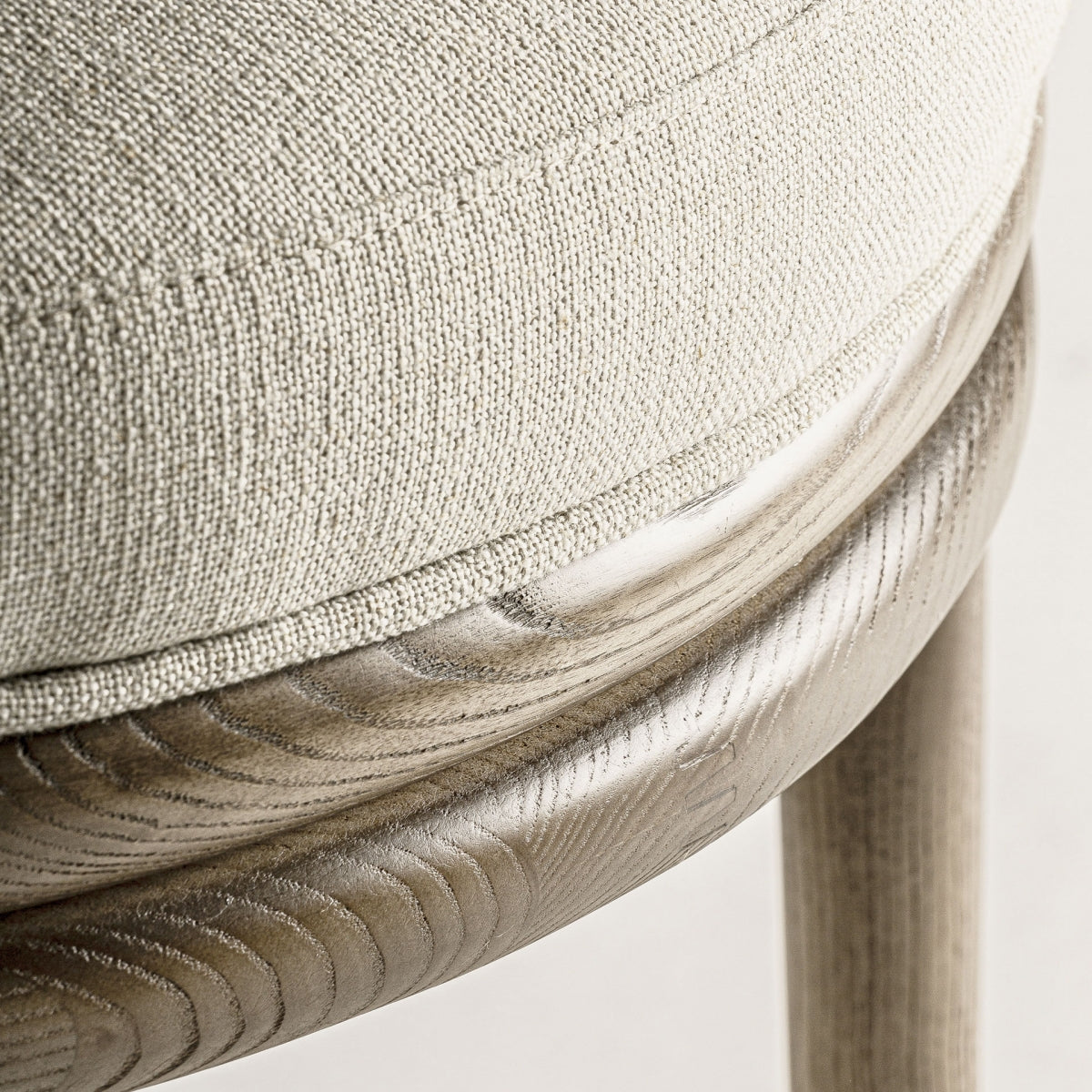 Primer plano del asiento redondo con tapizado beige texturizado y acolchado confortable.