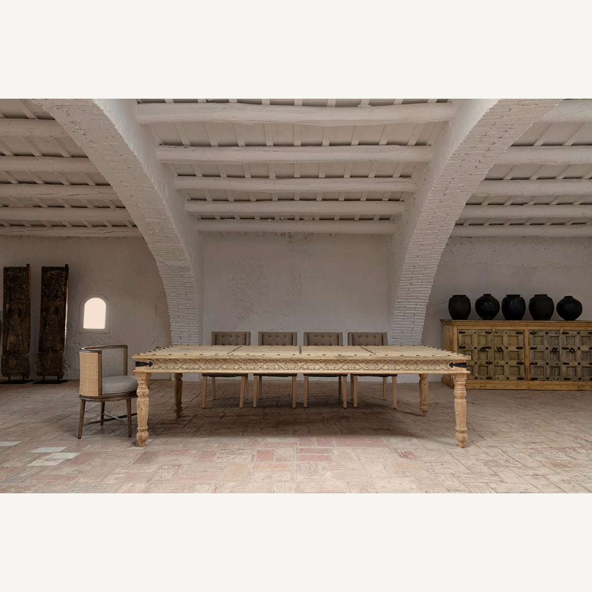 Silla Varaire integrada en comedor de estilo rústico con mesa de madera tallada y fondo neutro.