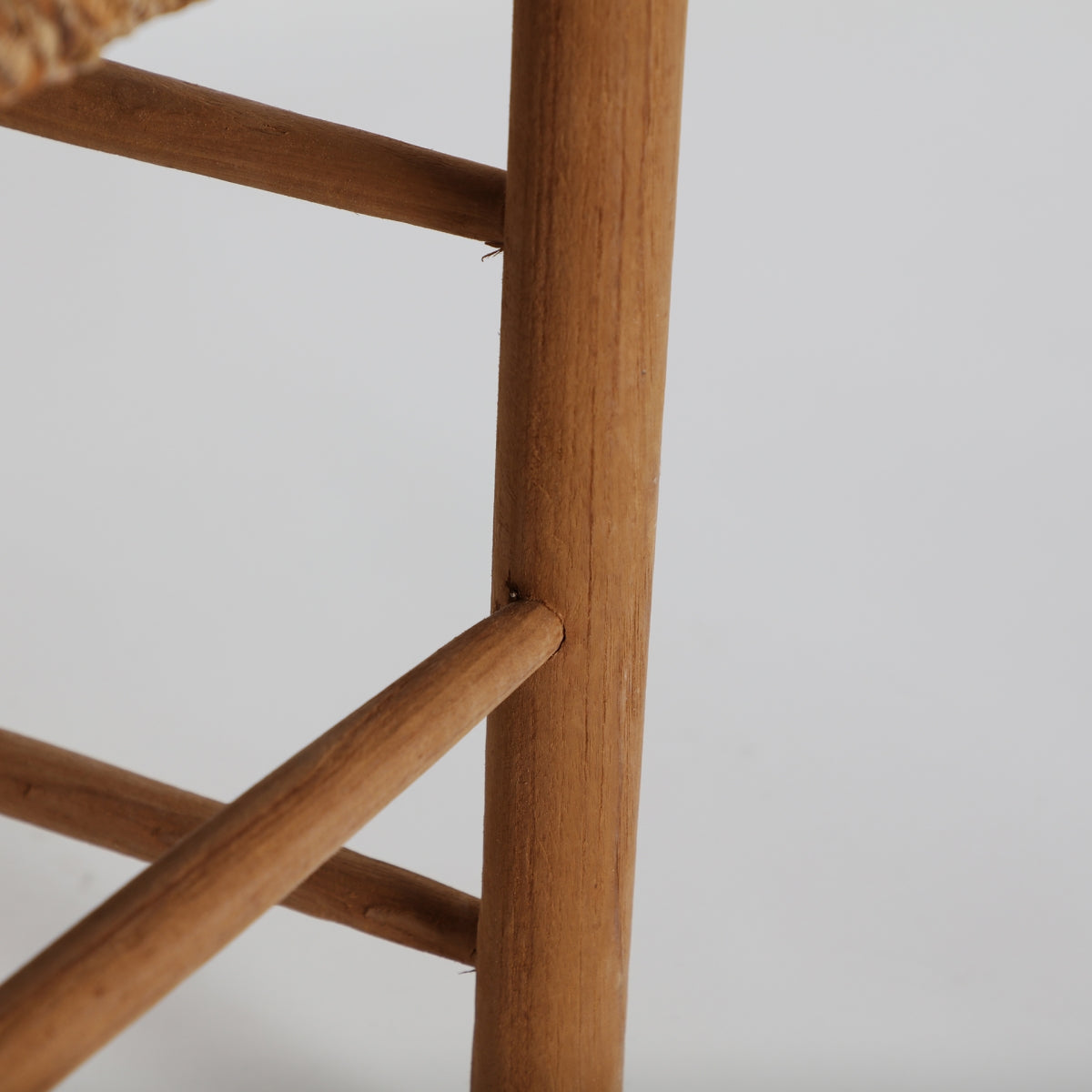 Detalle de la unión entre patas de madera en la silla Manhula, diseño simple de inspiración tradicional