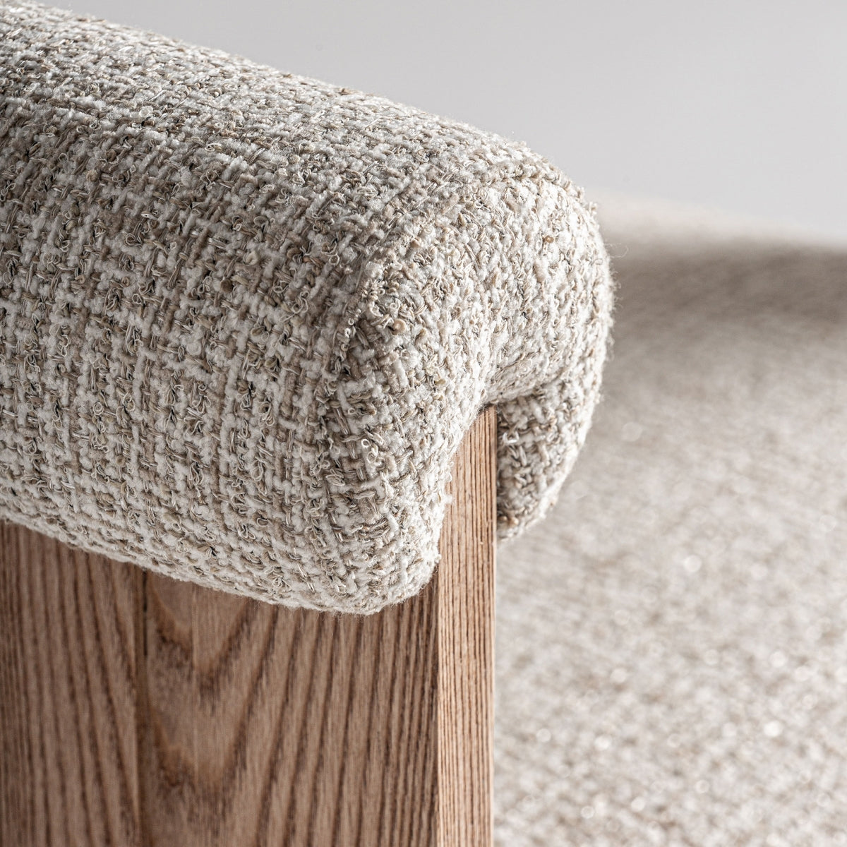 Detalle del tapizado en bouclé beige de textura gruesa sobre respaldo curvo