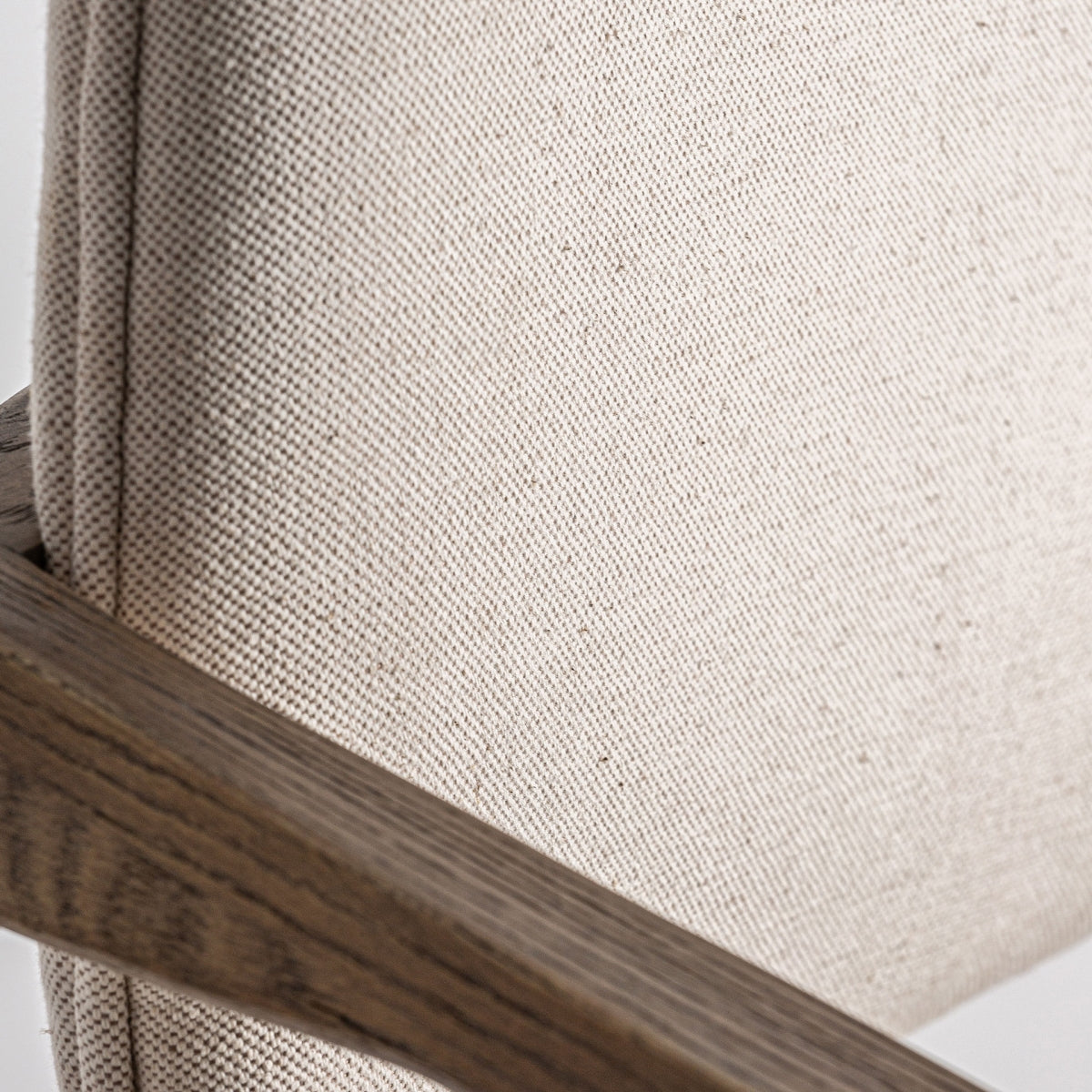 Primer plano del respaldo tapizado en lino beige con textura natural y costura sutil.