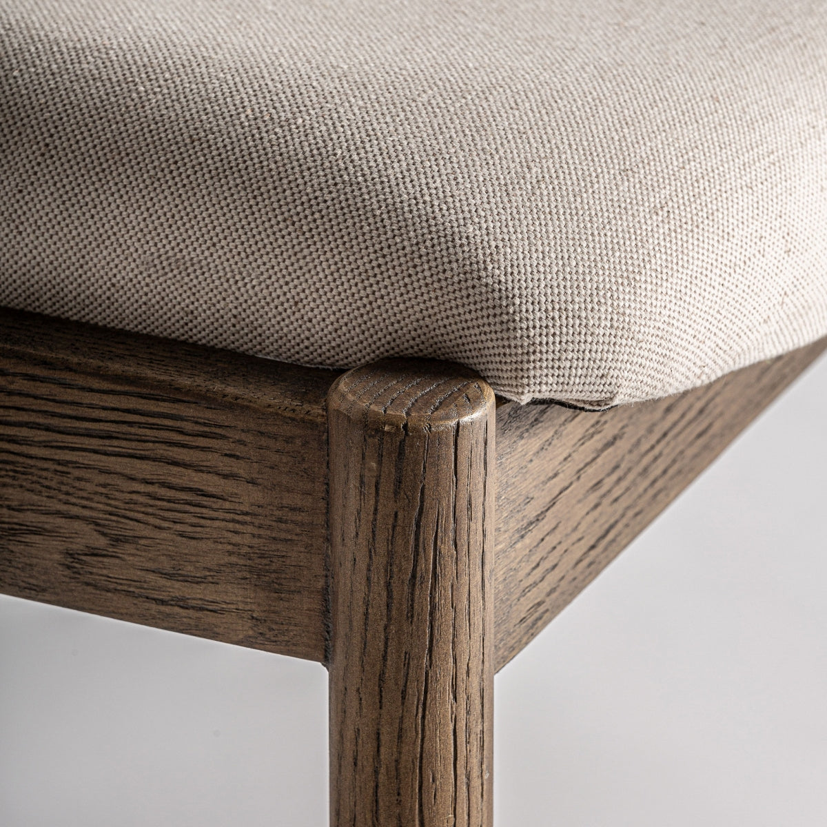 Detalle del asiento acolchado, tapizado en tejido beige y acabado cuidado.