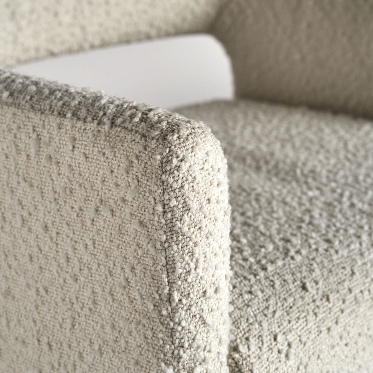 Detalle del apoyabrazos de la Silla Alvra en tejido bouclé blanco, textura suave y envolvente
