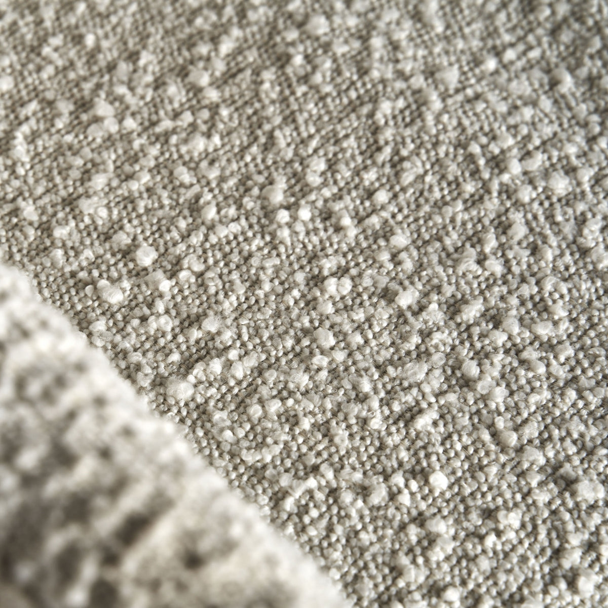 Primer plano de la textura bouclé blanco roto de la Silla Alvra, con detalle de su acabado textil artesanal