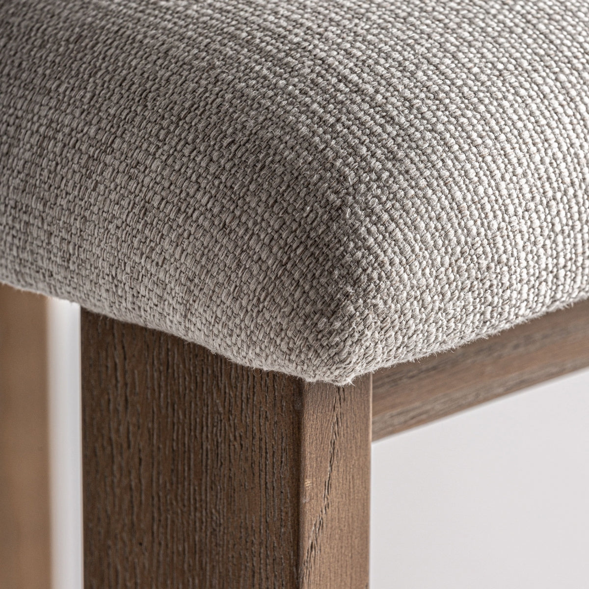 Detalle de asiento tapizado en lino natural sobre estructura de madera