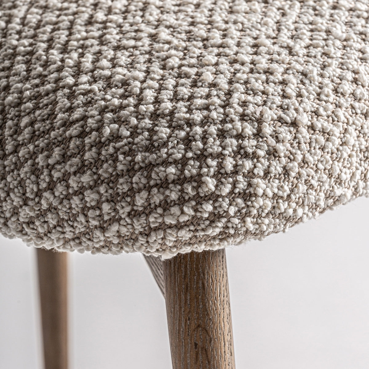 Detalle del asiento mullido en tejido bouclé beige de la silla Glorenza, textura cálida y confortable