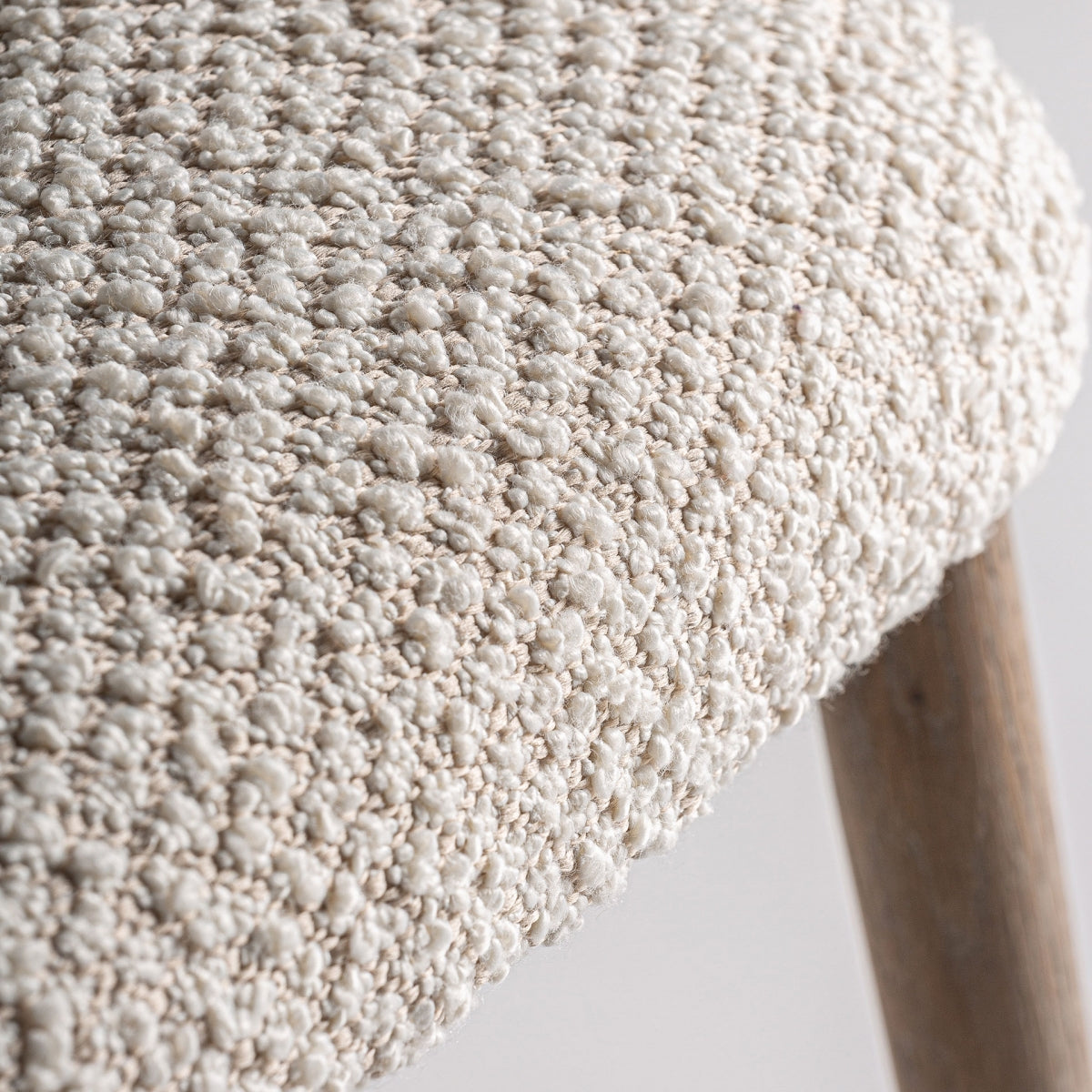 Detalle de textura del tapizado bouclé en tono natural, realce de calidad visual en la silla Glorenza