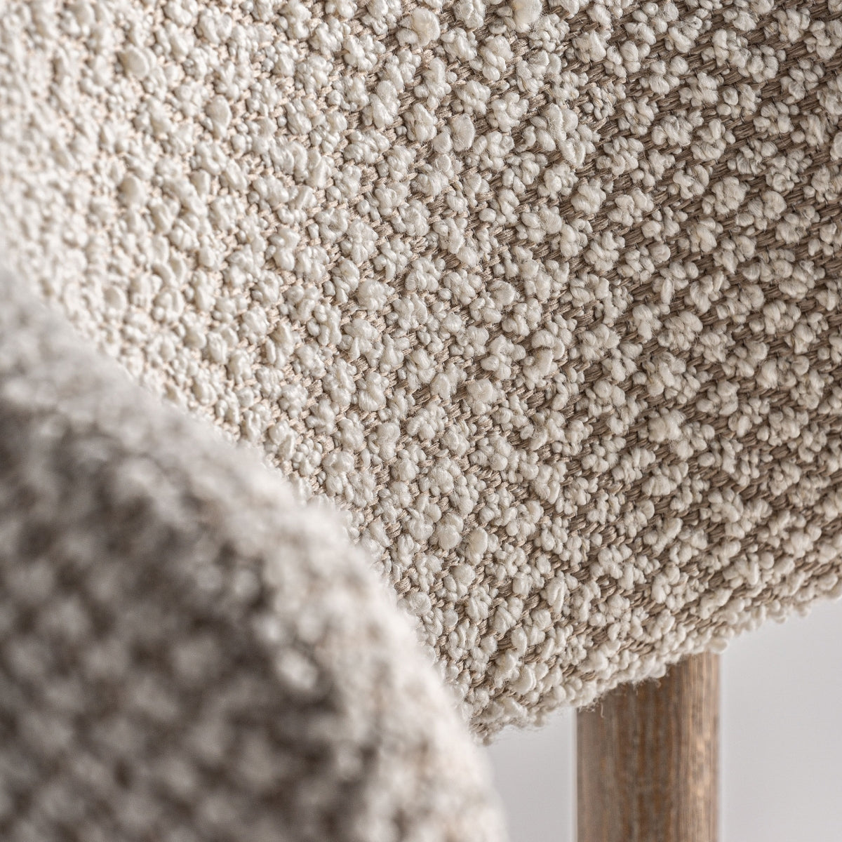Primer plano del respaldo tapizado en bouclé beige, detalle acogedor y elegante de la silla Glorenza
