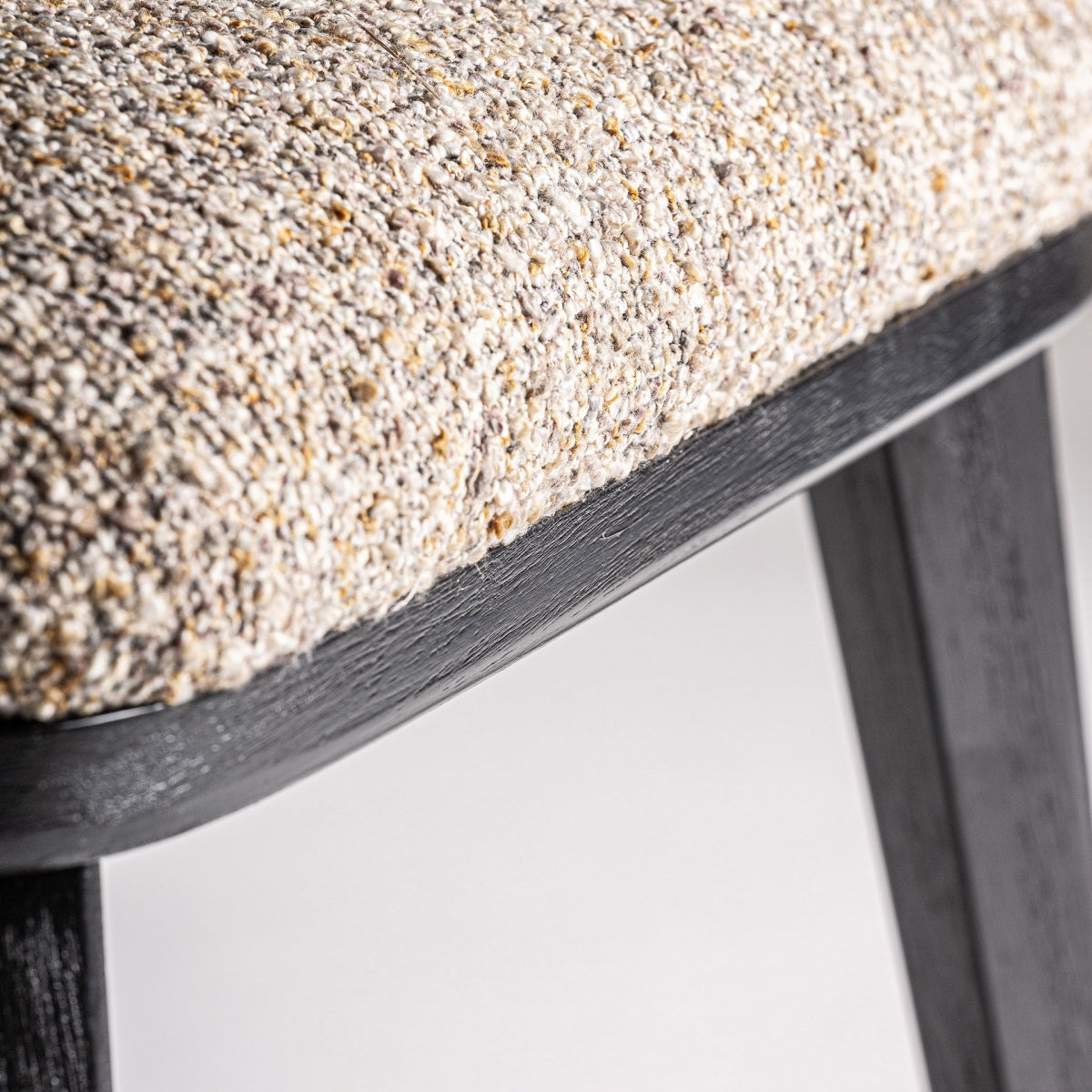 Primer plano de la base del asiento y pata en madera negra, estructura sólida y elegante.