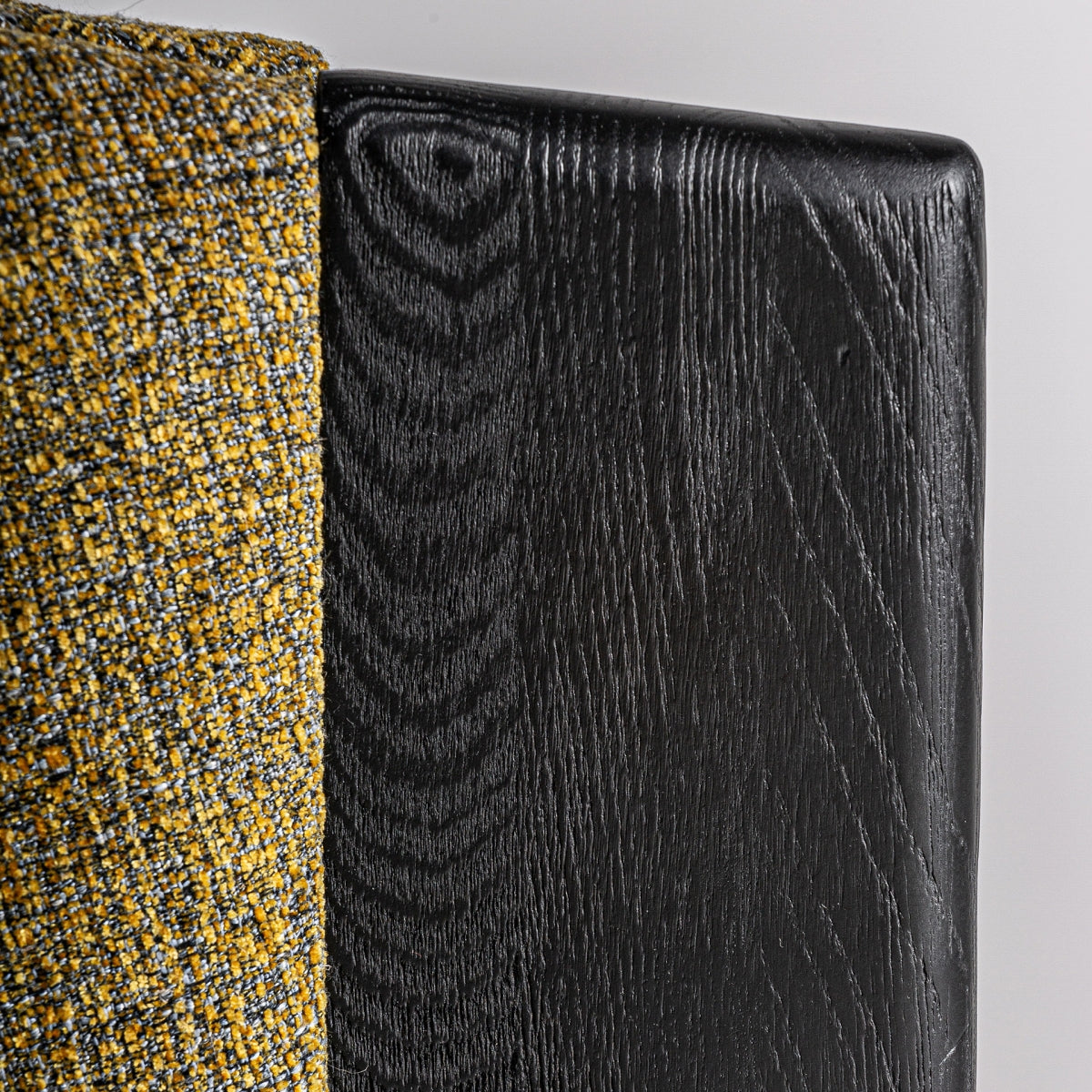 Contraste entre la textura del tapizado y la veta de la madera negra, estilo contemporáneo.