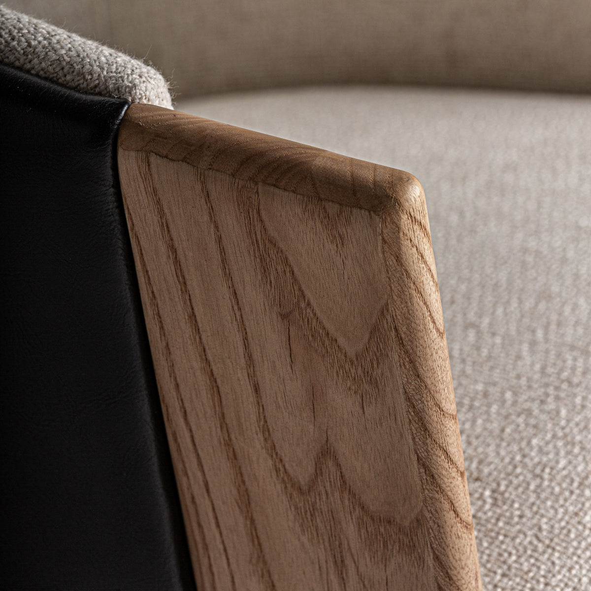 Detalle de los brazos de madera de roble con vetas visibles y tapizado beige suave