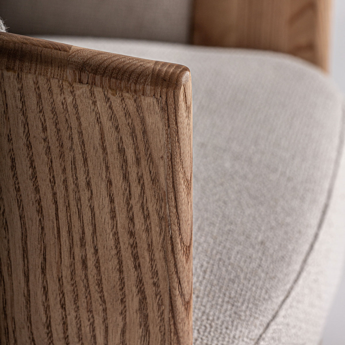 Detalle del apoyabrazos curvado en madera de roble, diseño moderno y envolvente