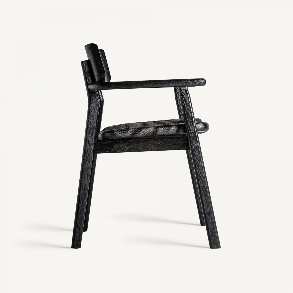 Vista lateral de silla negra, asiento trenzado y estructura de madera