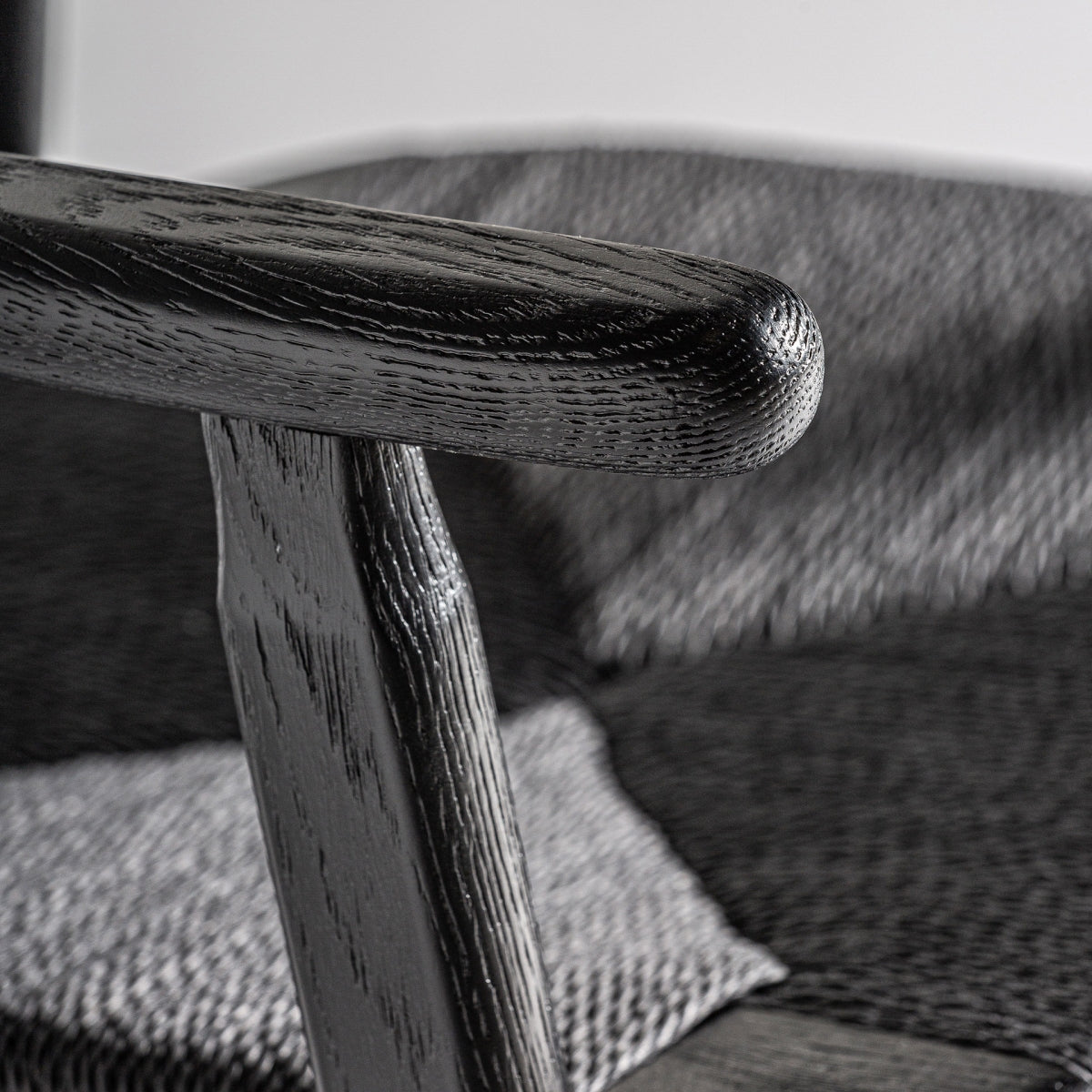 Detalle del brazo curvo de madera negra, acabado liso y artesanal