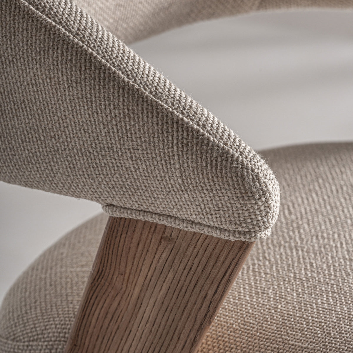 Primer plano del ángulo de unión entre tapizado y pata de madera en silla de diseño nórdico.