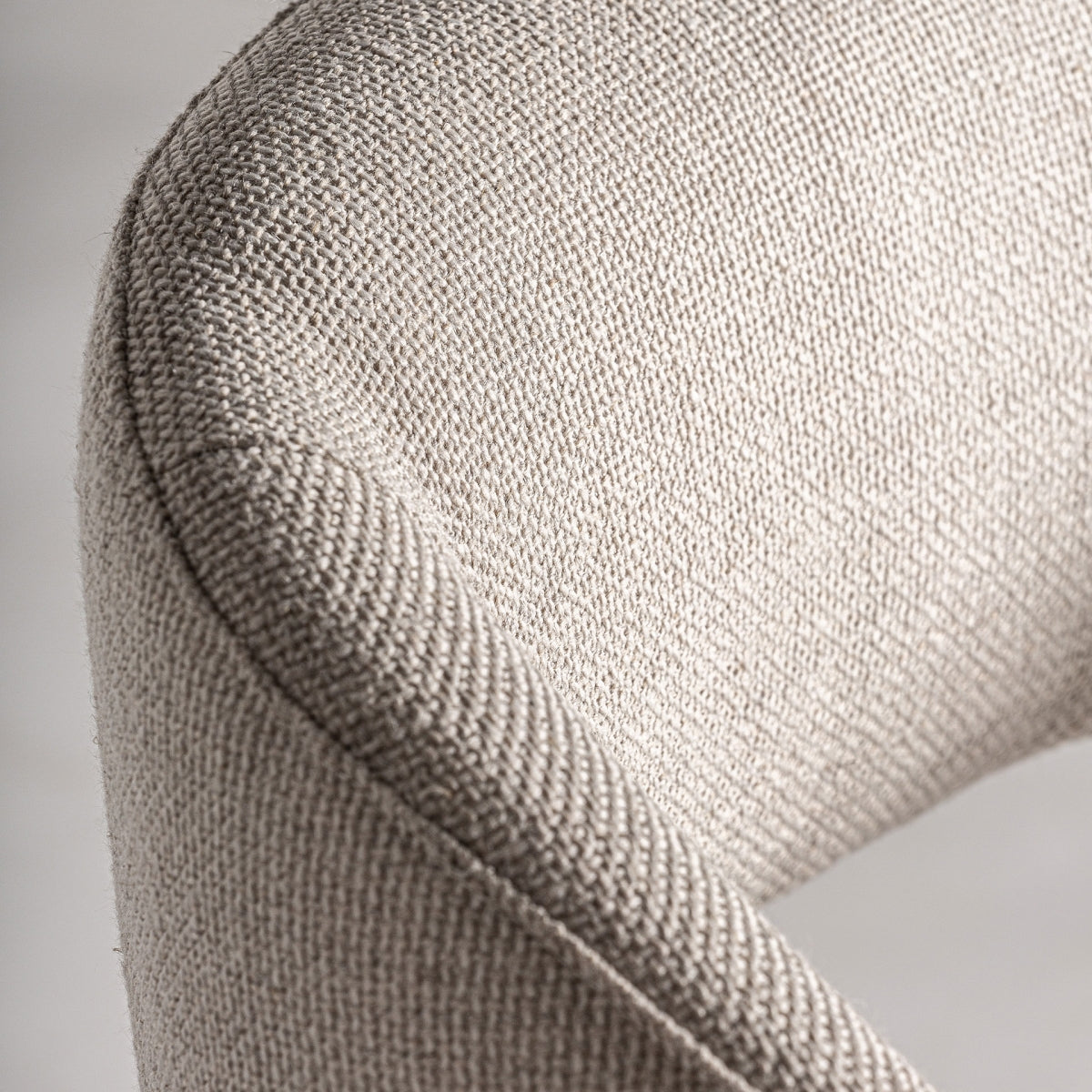 Detalle del respaldo tapizado en tejido beige con costura visible y forma ergonómica.