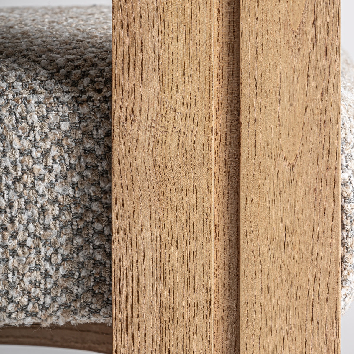 Primer plano del asiento tapizado en bouclé beige sobre estructura de madera clara.