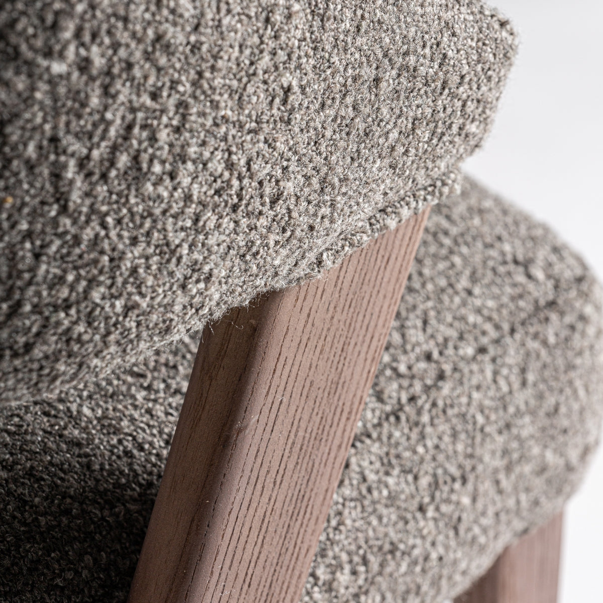 Encuentro entre tapizado de bouclé marrón y madera natural, detalle de calidad