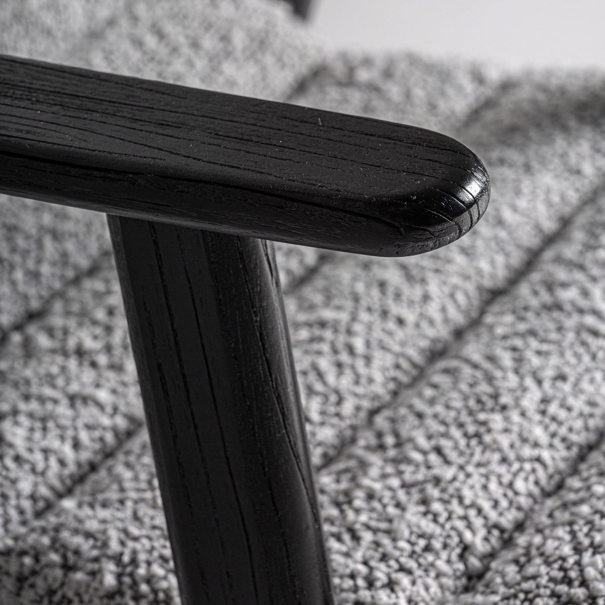 Detalle del brazo en madera negra sobre tapizado boucle texturizado