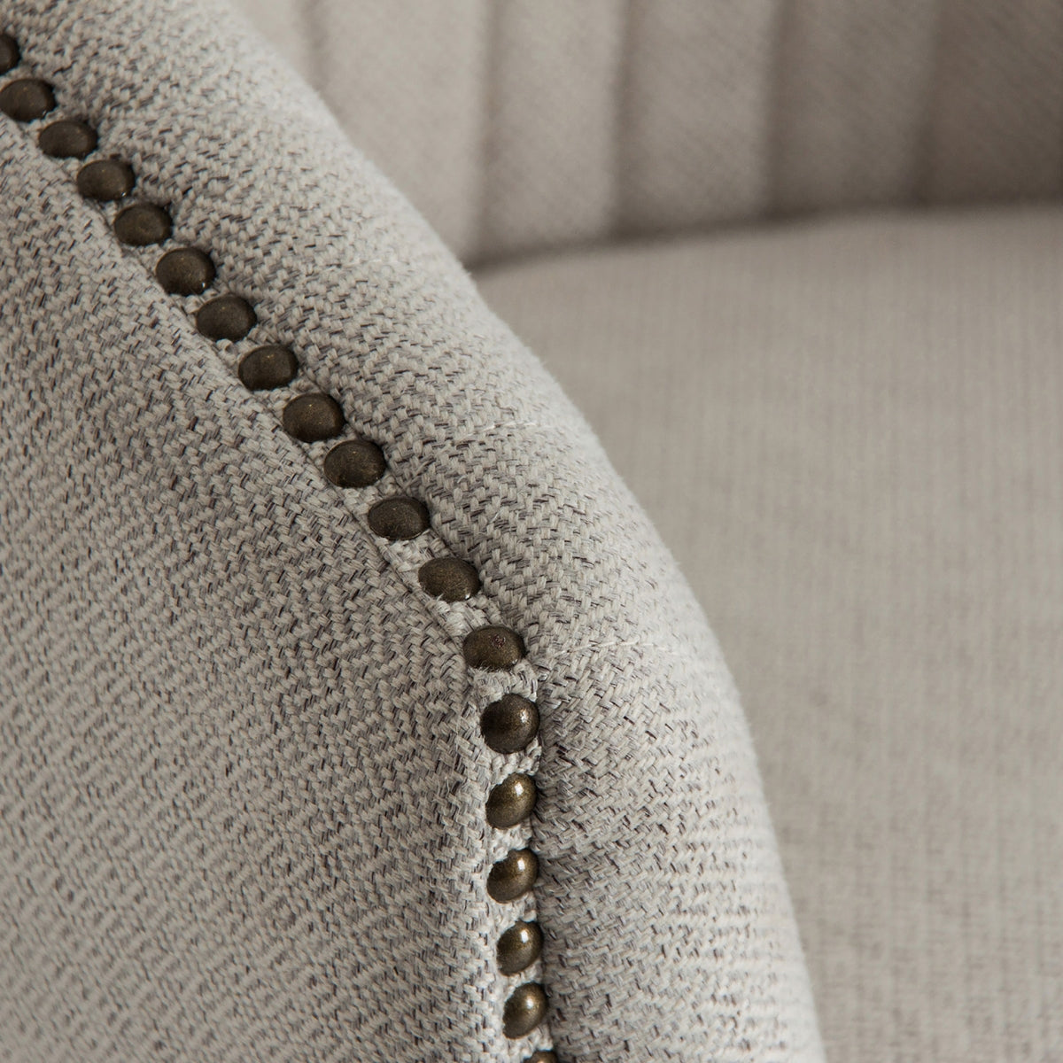 Detalle en primer plano del tapizado gris con tachuelas metálicas del sillón Neive