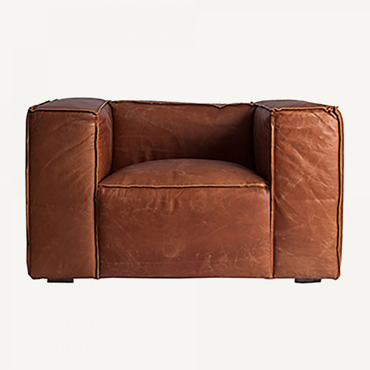 Sillón de cuero natural envejecido, vista frontal con asiento profundo y brazos rectos, estilo industrial cálido