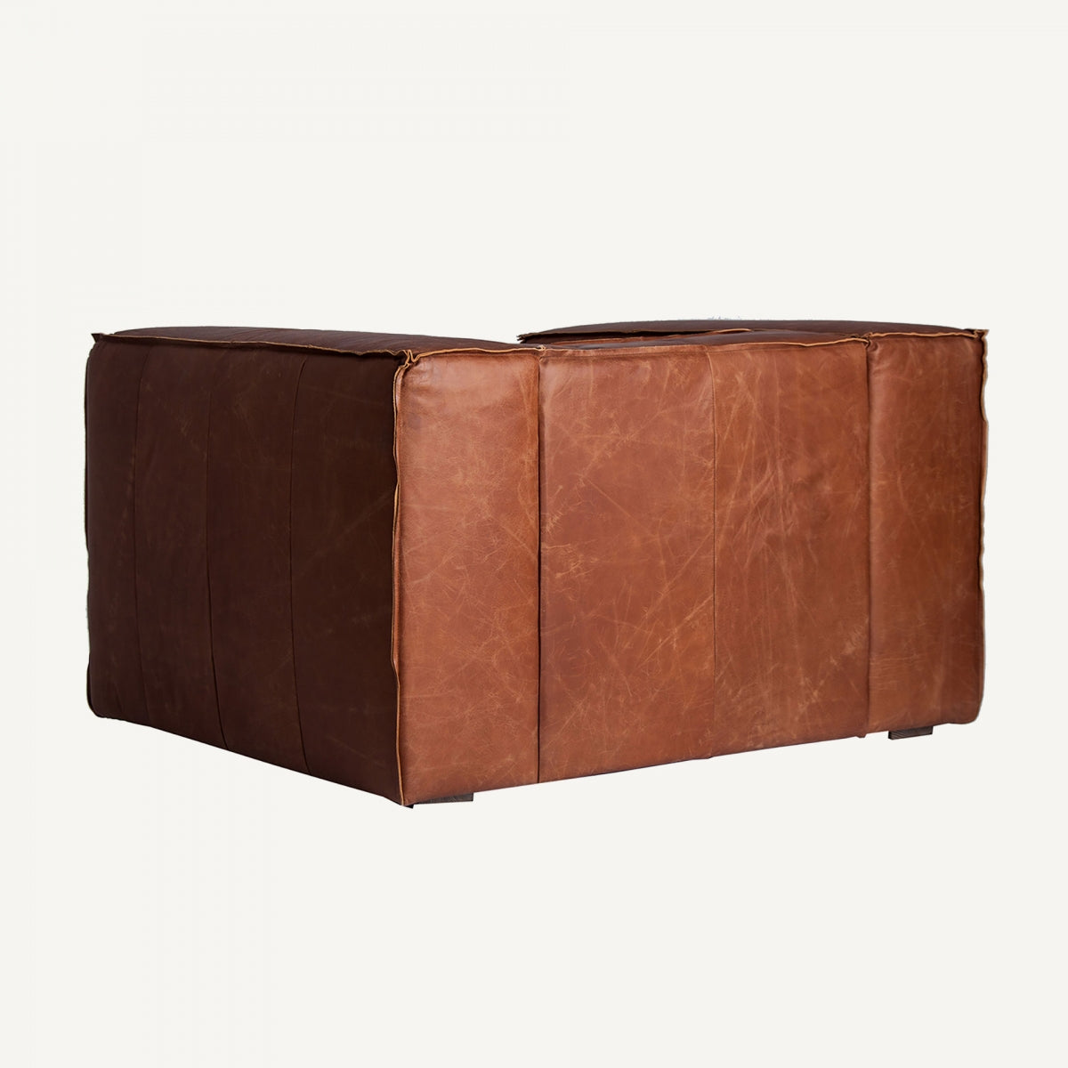 Sillón de cuero envejecido en perspectiva, destaca el volumen cúbico y el acolchado generoso, diseño masculino