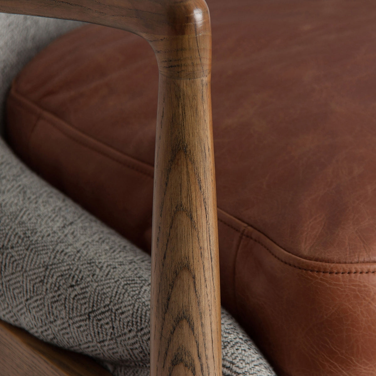 Primer plano del brazo y cojín de piel marrón de la butaca ELATI, contraste de materiales nobles, estilo cálido contemporáneo.