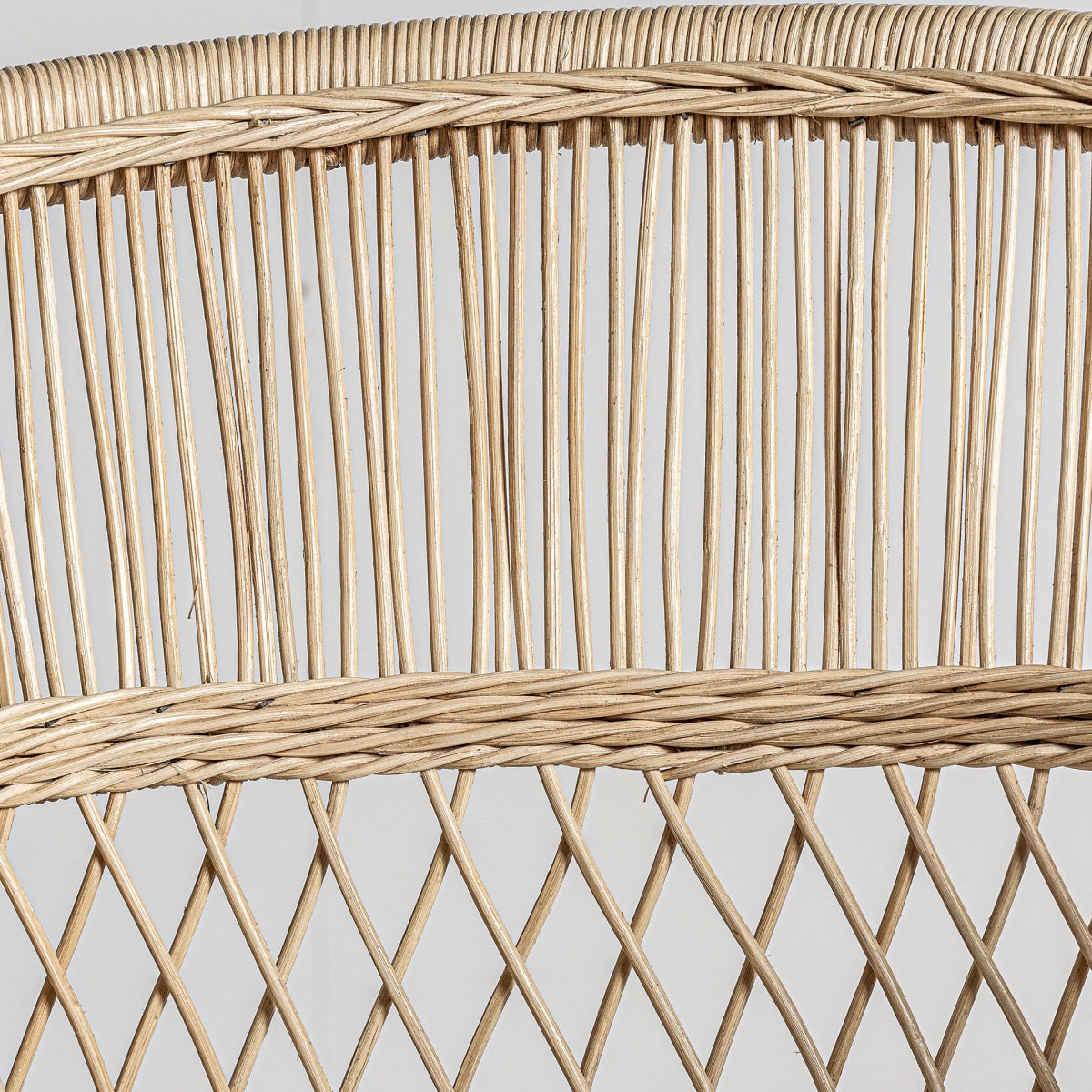 Detalle de la esquina del respaldo en ratán. Sillón Elna en ratán natural con cojín desenfundable de algodón, estilo mediterráneo cálido y ligero.