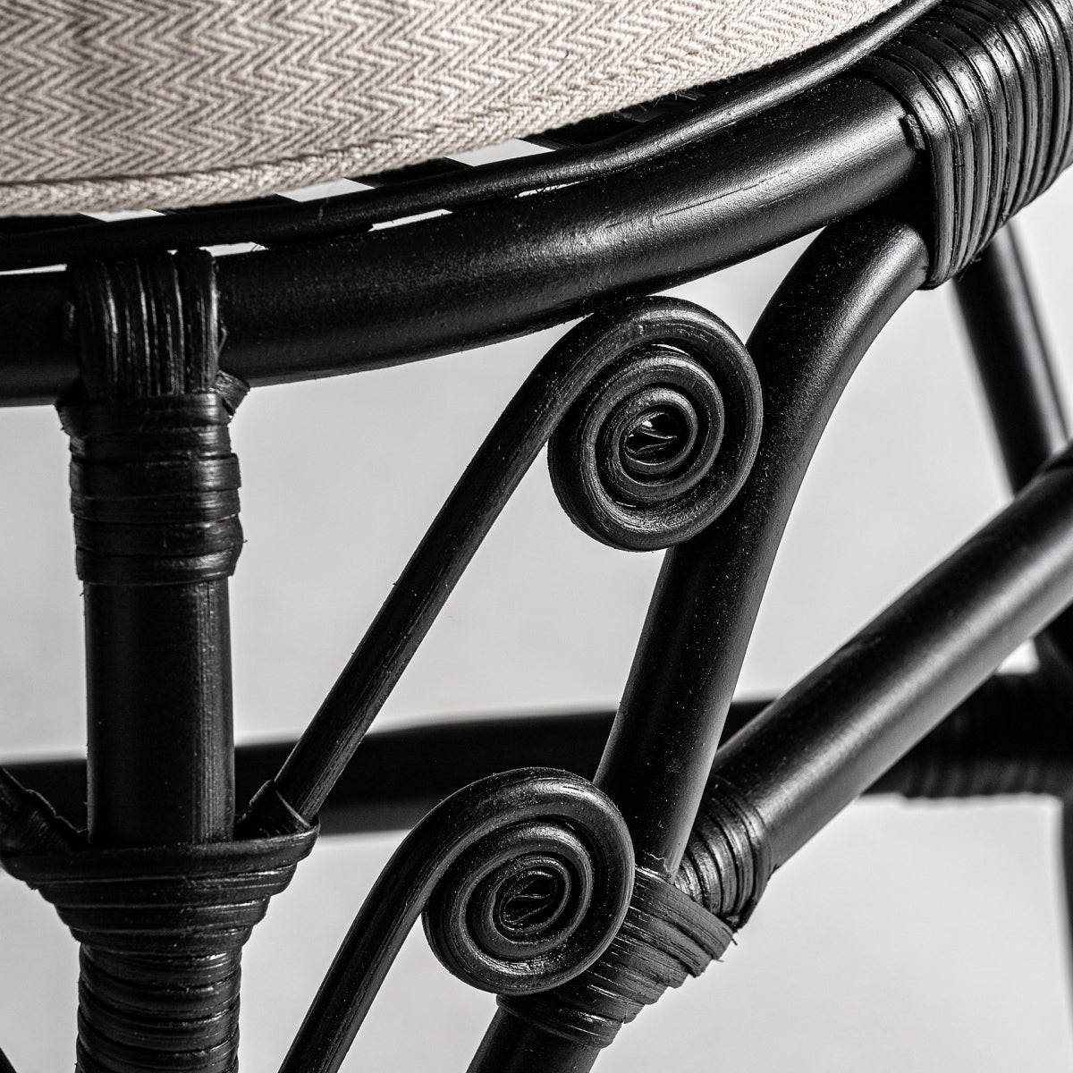 Detalle de la estructura inferior del sillón con espirales decorativas en ratán negro