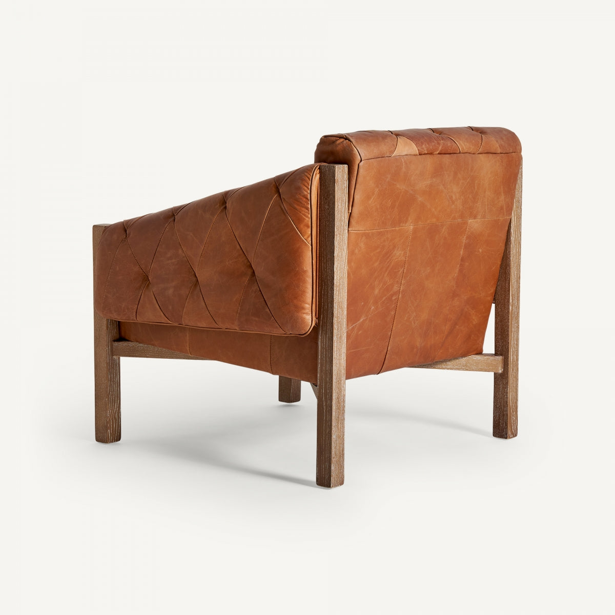 Vista trasera de butaca de cuero marrón con respaldo acolchado y patas de madera clara, boutique interiorismo Vical