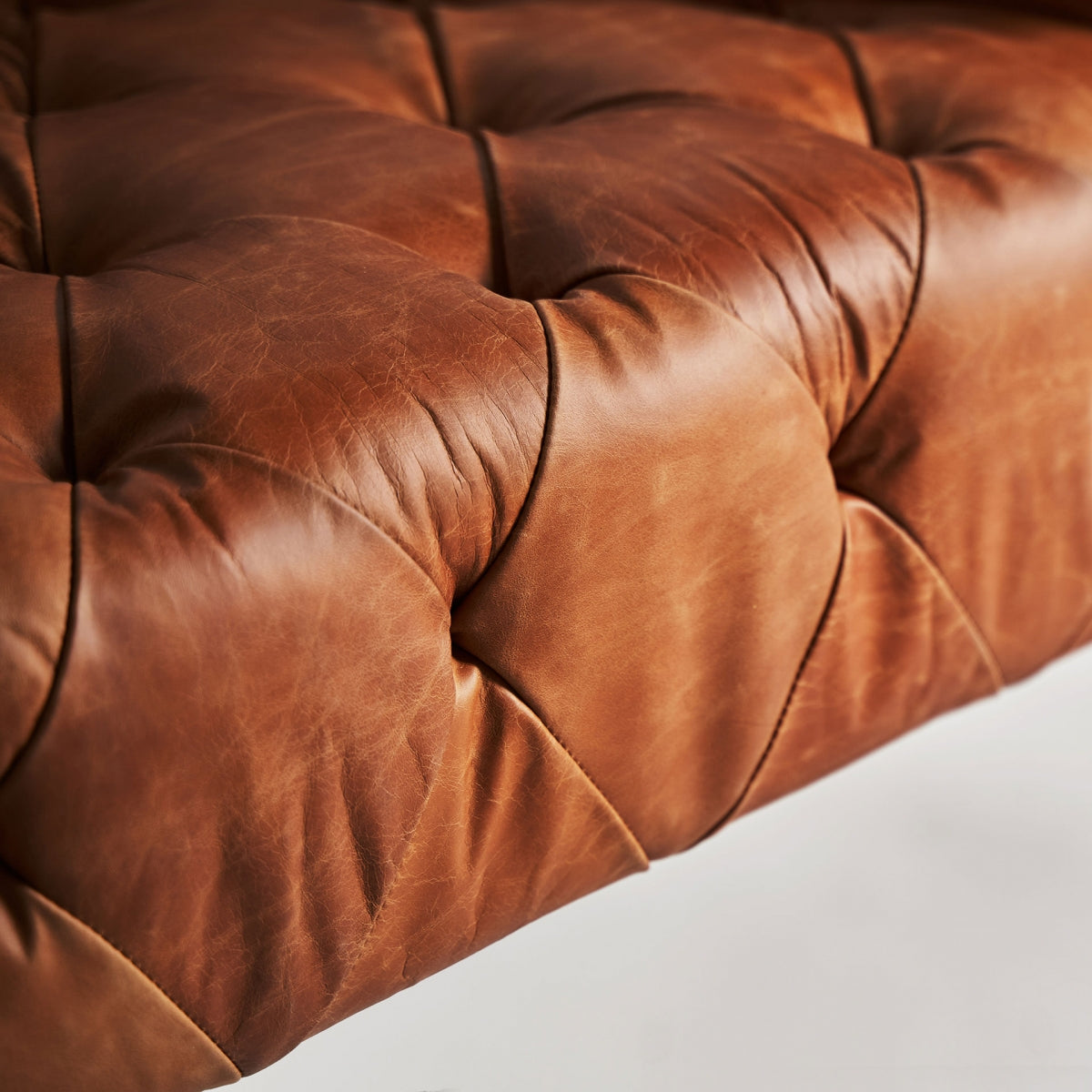 Detalle del asiento en cuero marrón con acolchado tipo capitoné, estilo vintage, boutique interiorismo Vical