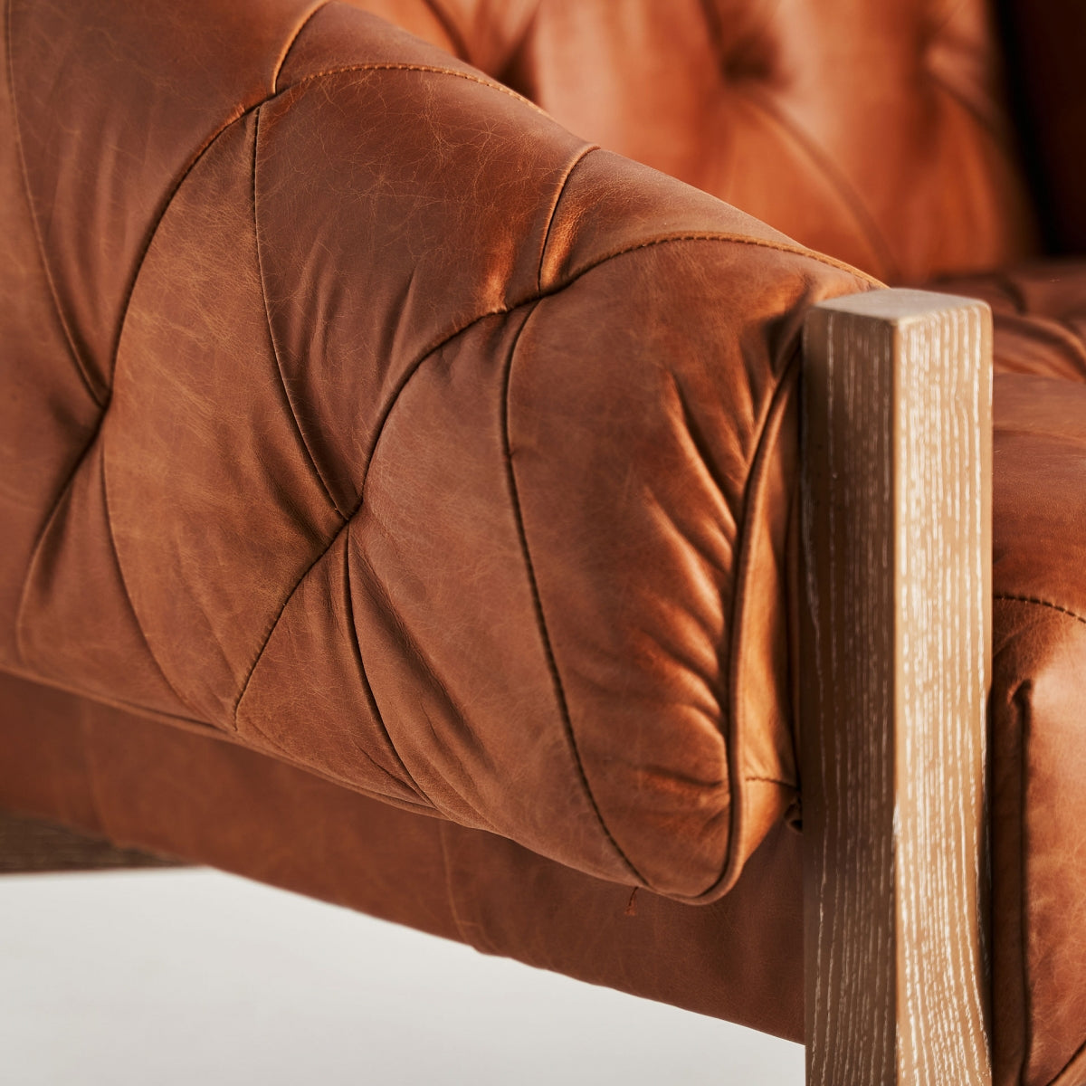 Detalle del brazo tapizado en cuero con efecto envejecido y estructura de madera vista, boutique interiorismo Vical